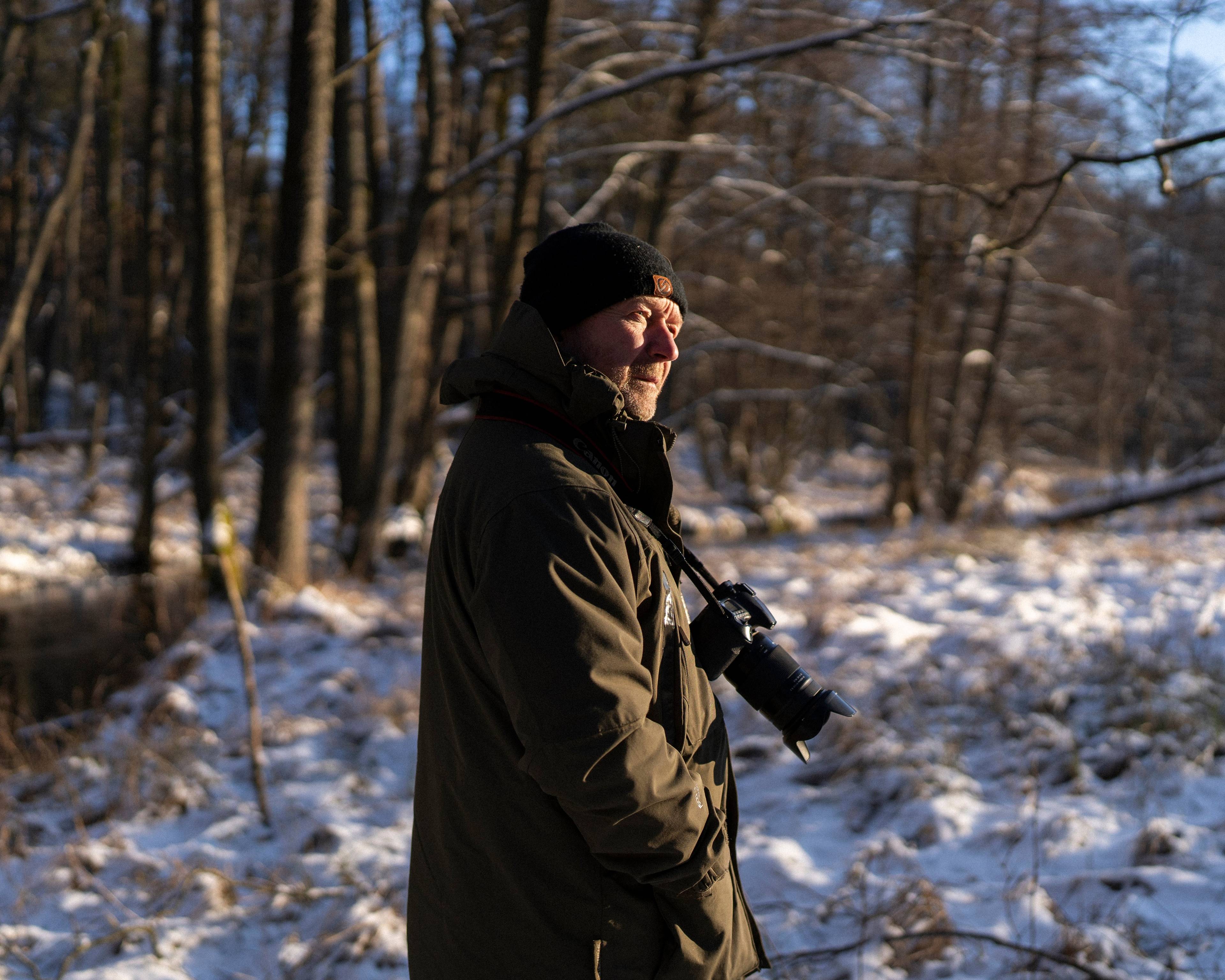 Mężczyzna z aparatem fotograficznym w zaśnieżonym lesie