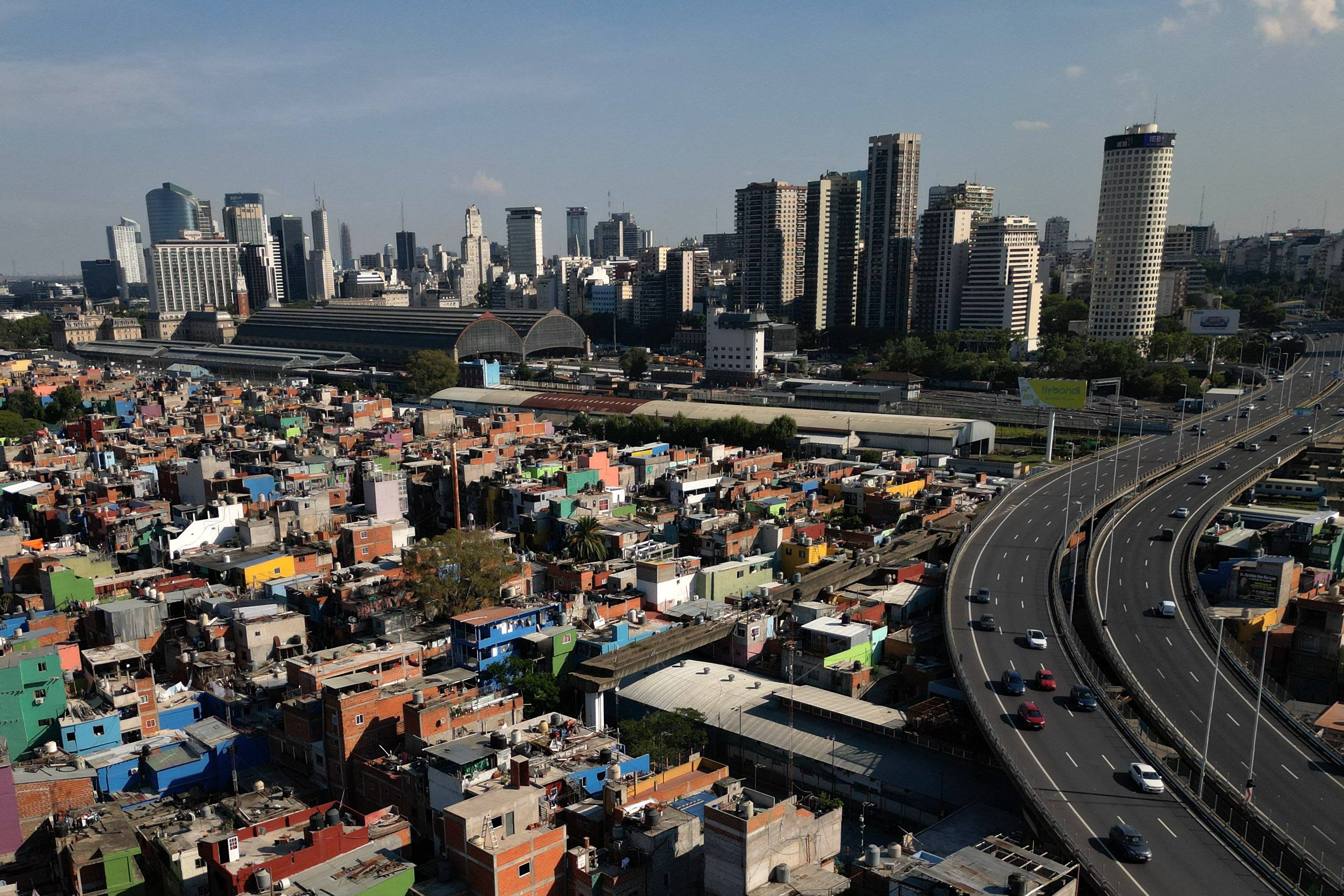 Widok na Buenos Aires, na pierwszym planie domy niższych klas społecznych i autostrada, na drugim planie wielopiętrowe nowoczesne budynki