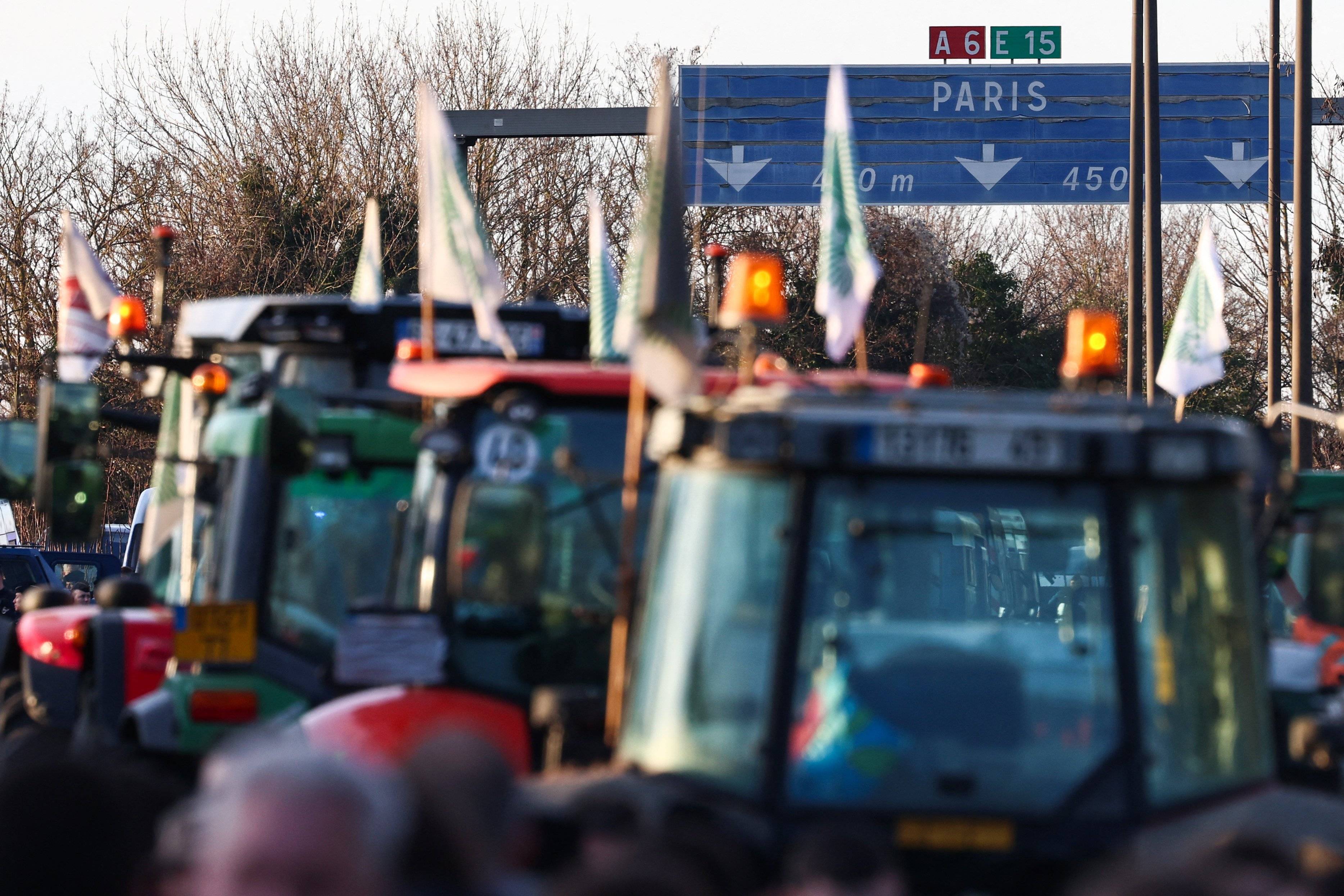 rolnicze ciągniki jadą autostradą, drogowskaz pokazuje kierunek na Paryż