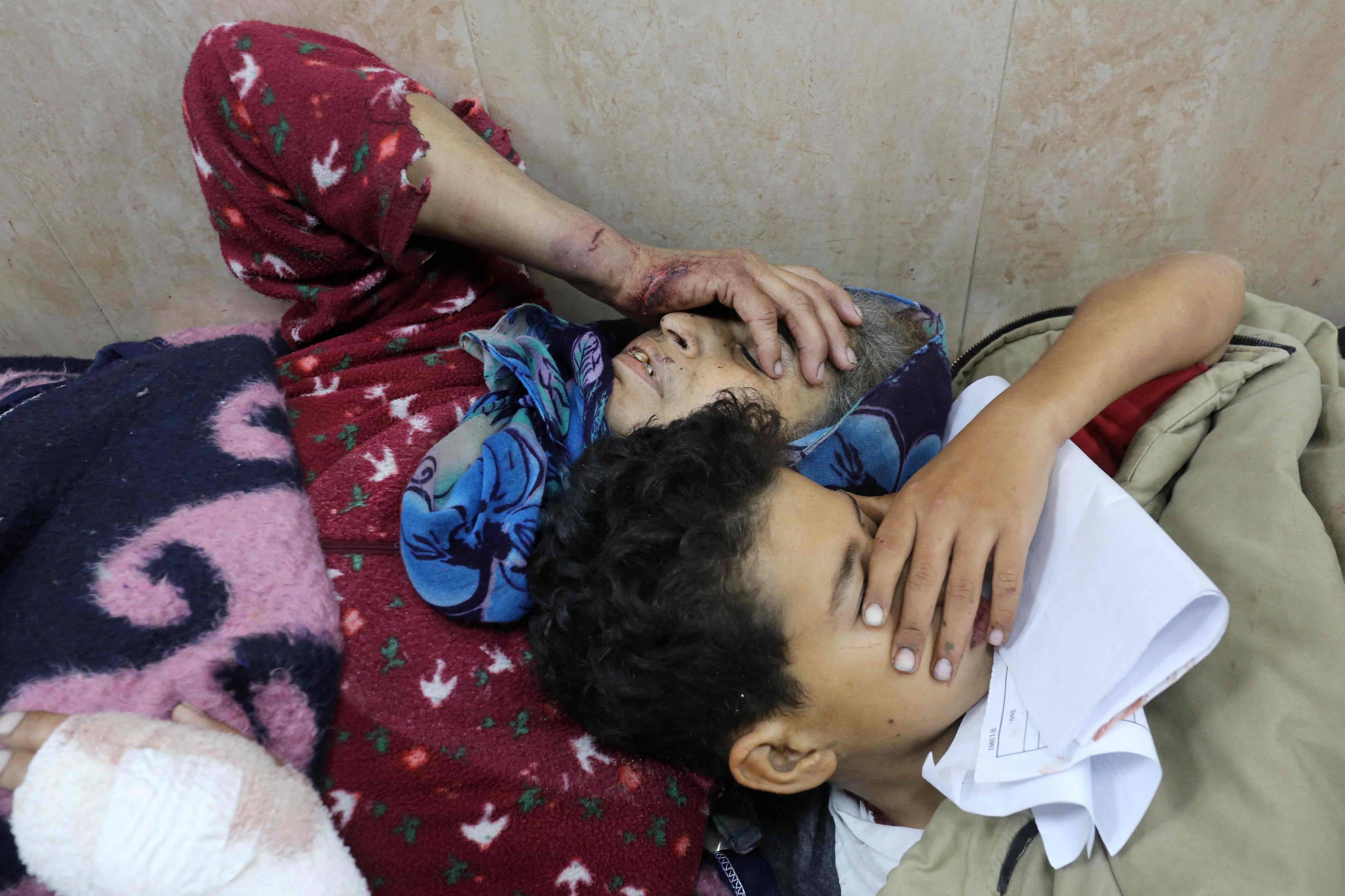 Kobieta i chłopiec leżą obok siebie na łóżku szpitalnym trzymając się za głowy. Streaf Gazy
