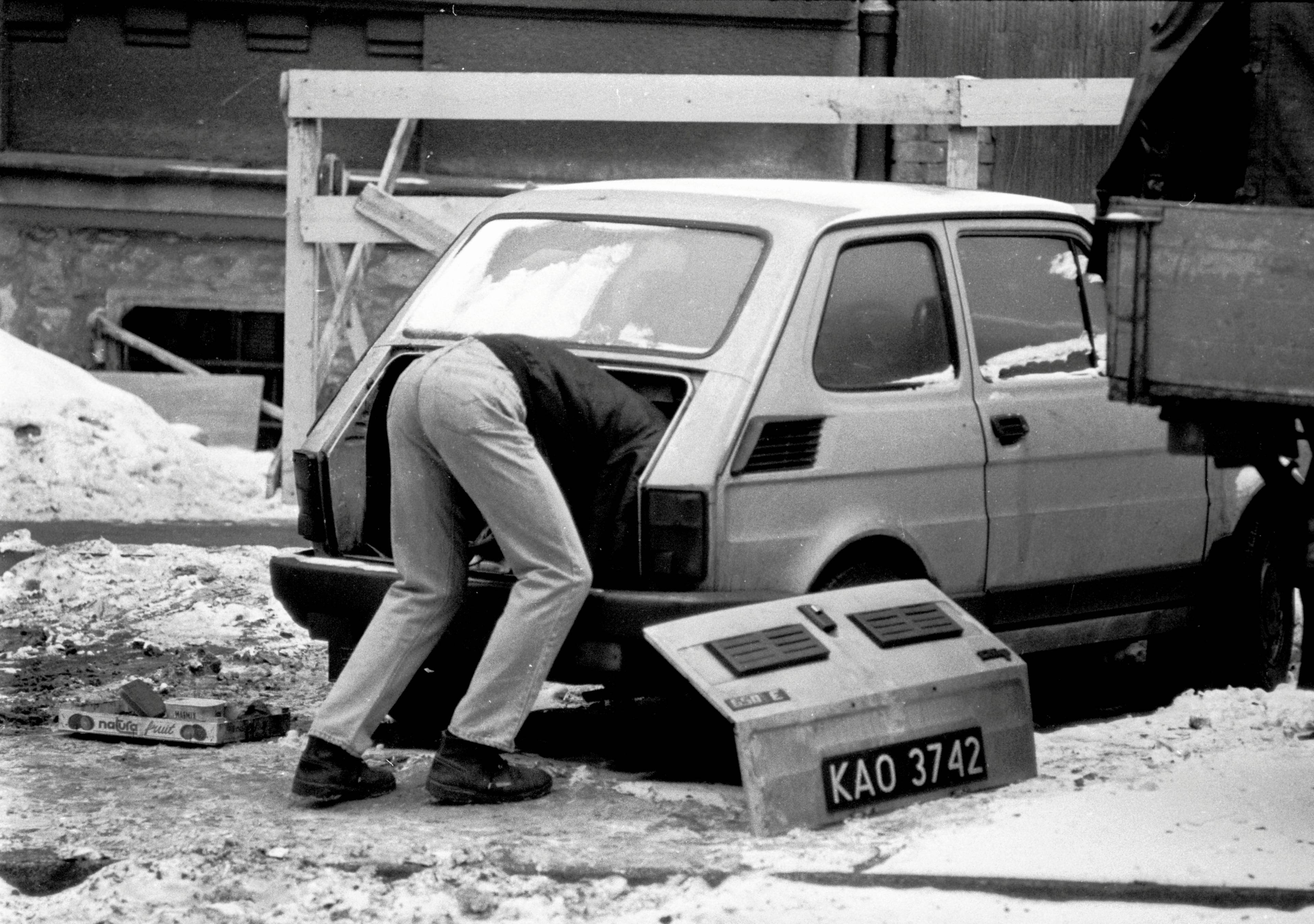 Mężczyzna naprawia silnik samochodu Fiat 126p