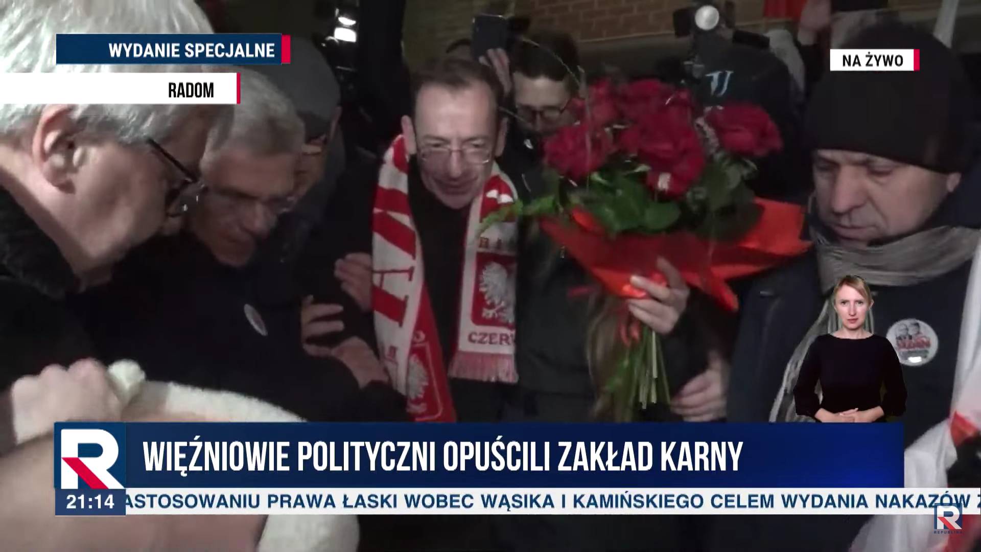 Kaminski w szaliku z napisem Polska z kwiatami wychodzi z więzienia w Radomiu