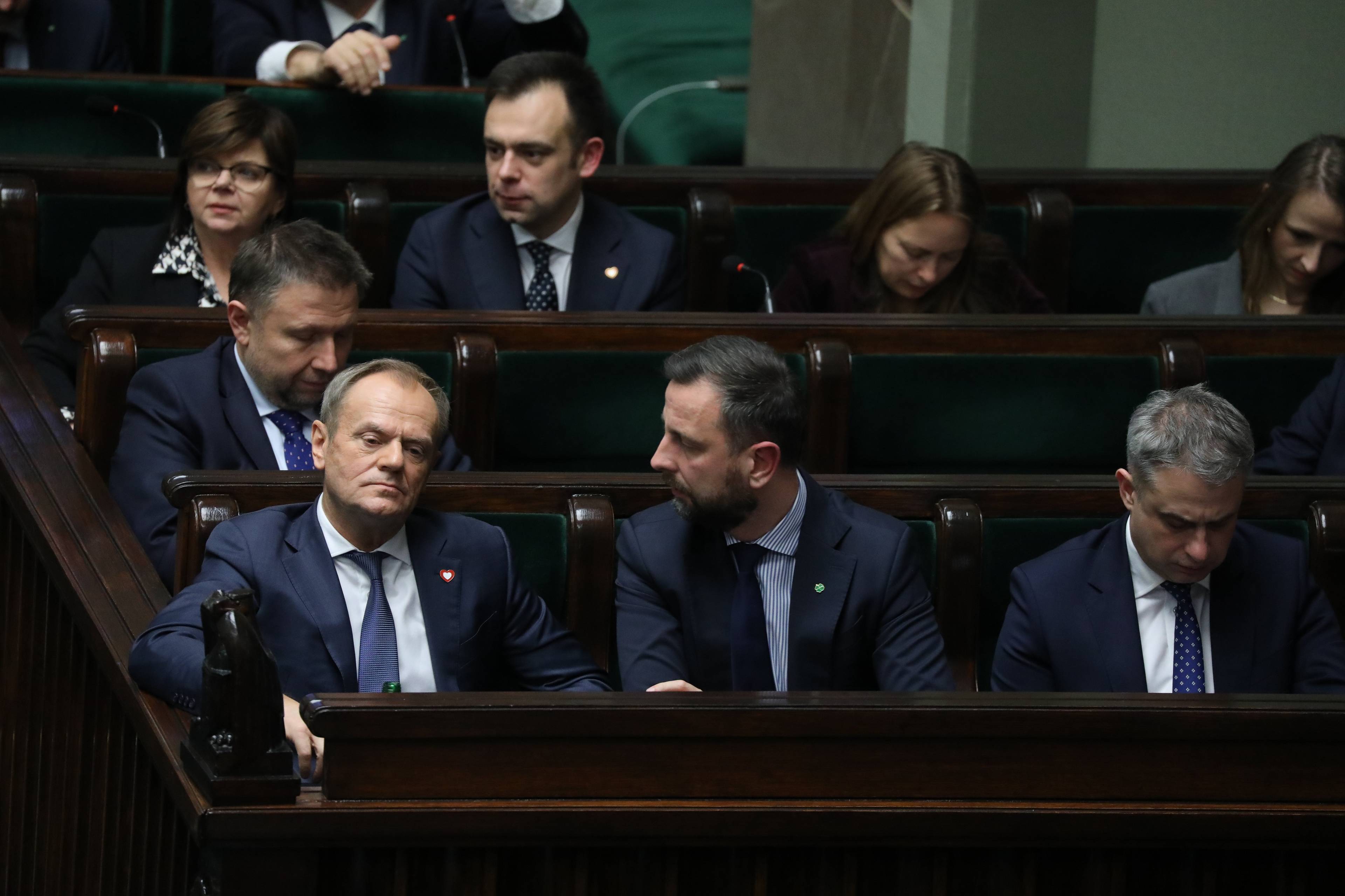 Członkowie rządu siedzą na swoich miejscach w Sejmie. Na pierwszym planie premier Tusk i wicepremierzy Kosiniak-Kamysz i Gawkowski. W trzecim rzędzie minister finansów Andrzej Domański