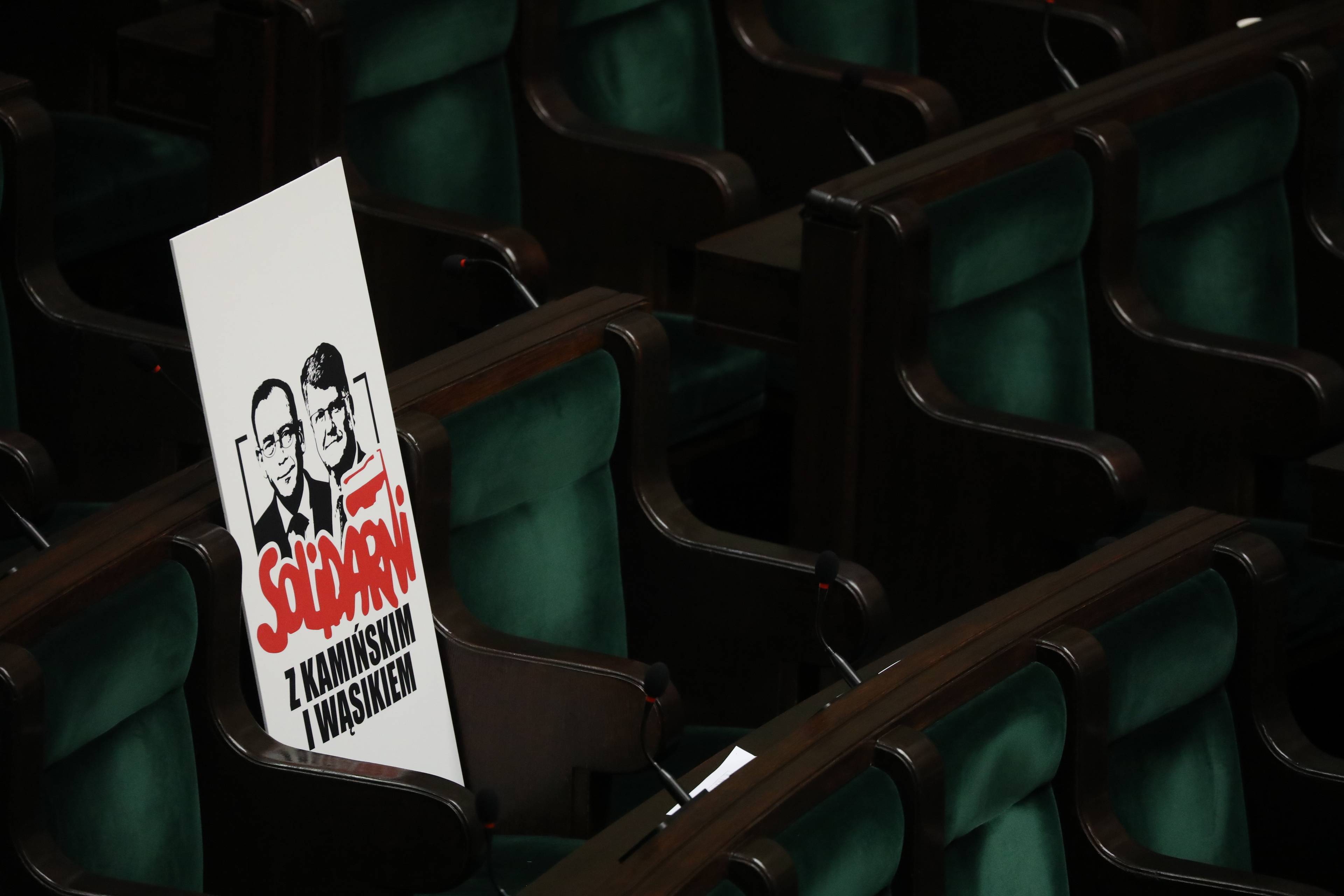 Na miejscu dla posłów na sali plenarnej Sejmu leży transparent z napisem "Solidarni z Wąsikiem i Kamińskim"