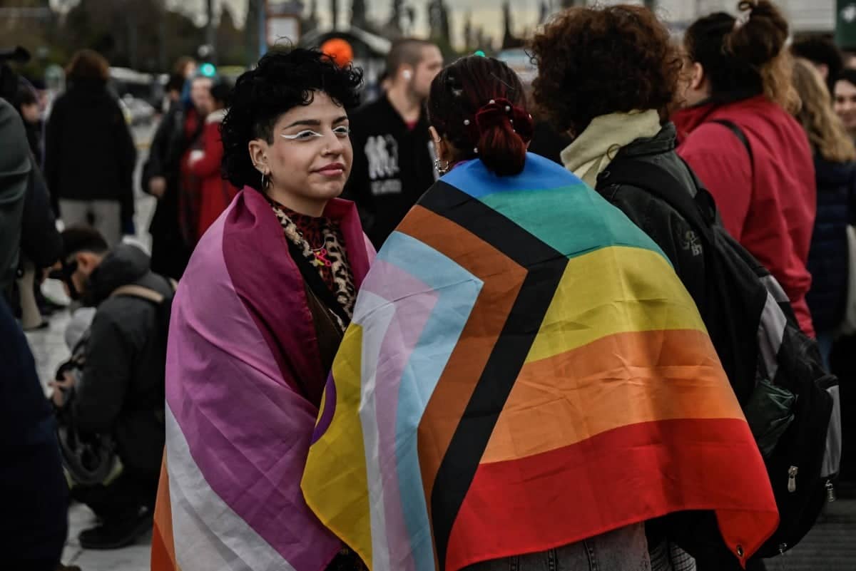 Dwie osoby owiniete w tęczowie flagi, symbol społeczności LGBT