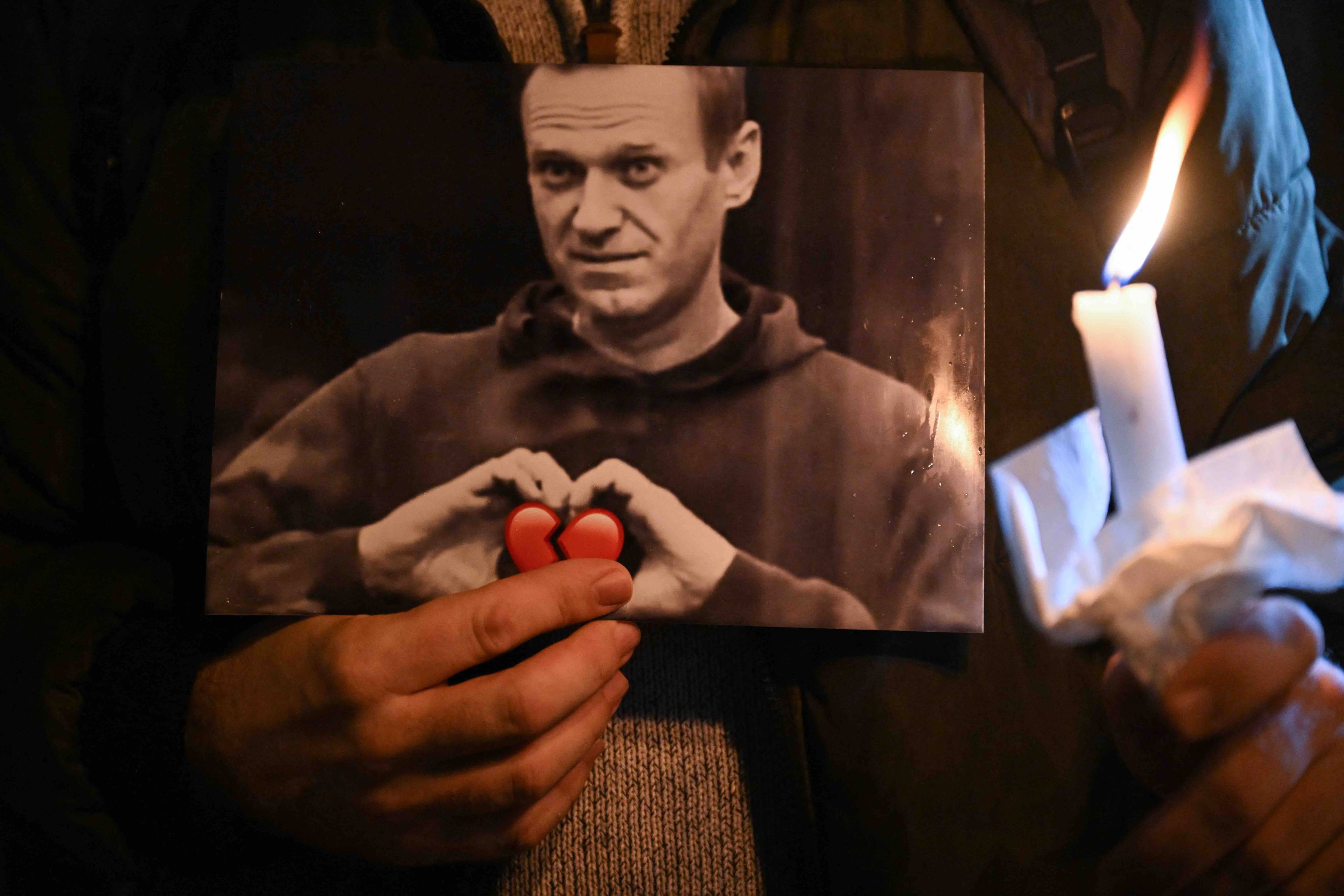 Uczestnik manifestacji trzyma w rękach świecę i zdjęcie Aleksieja Nawalnego, który układa dłonie w kształt serca