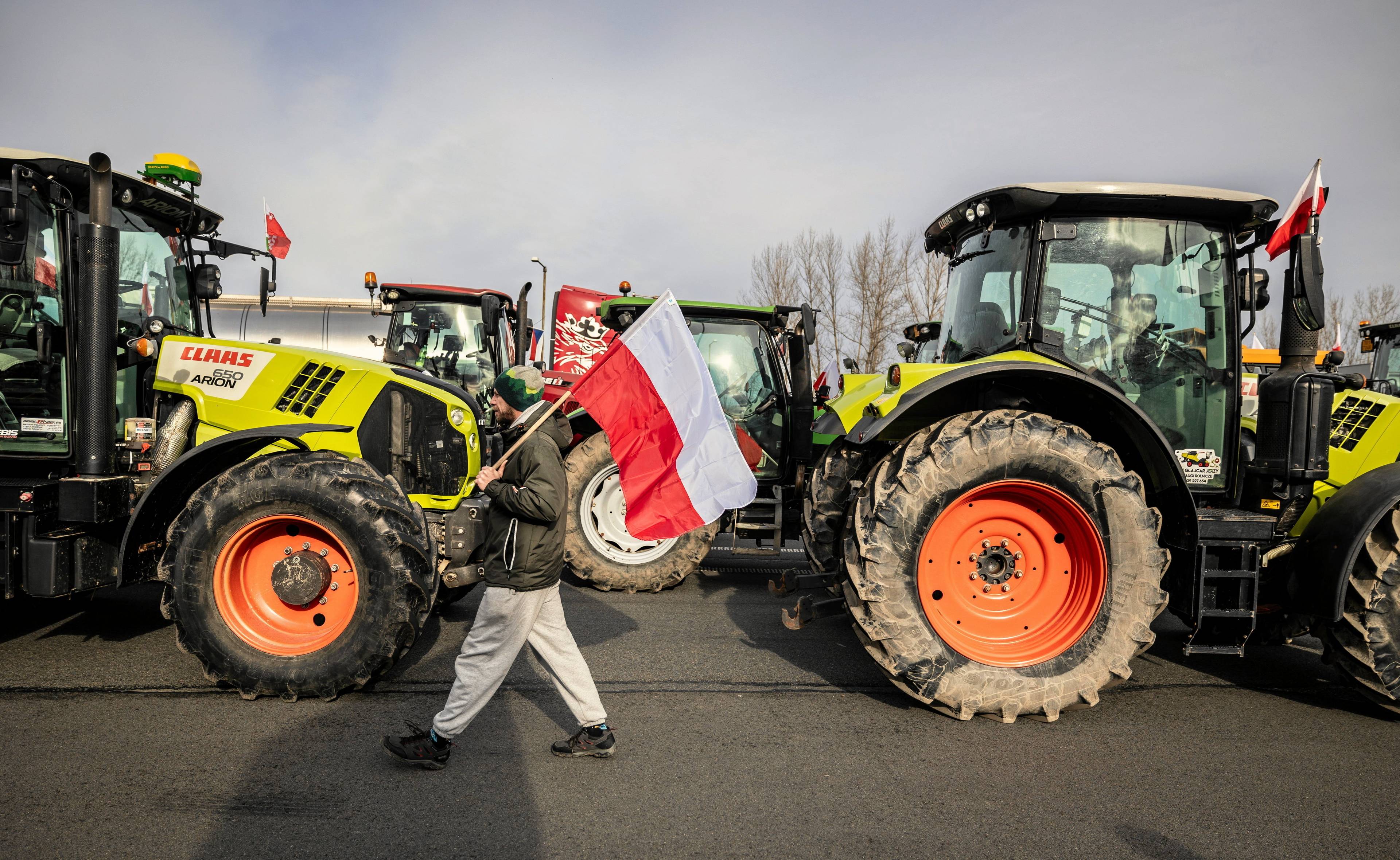 Protest rolników w Cieszynie. Dwa traktory, a pomiędzy nimi mężczyzna z biało-czerwoną flagą