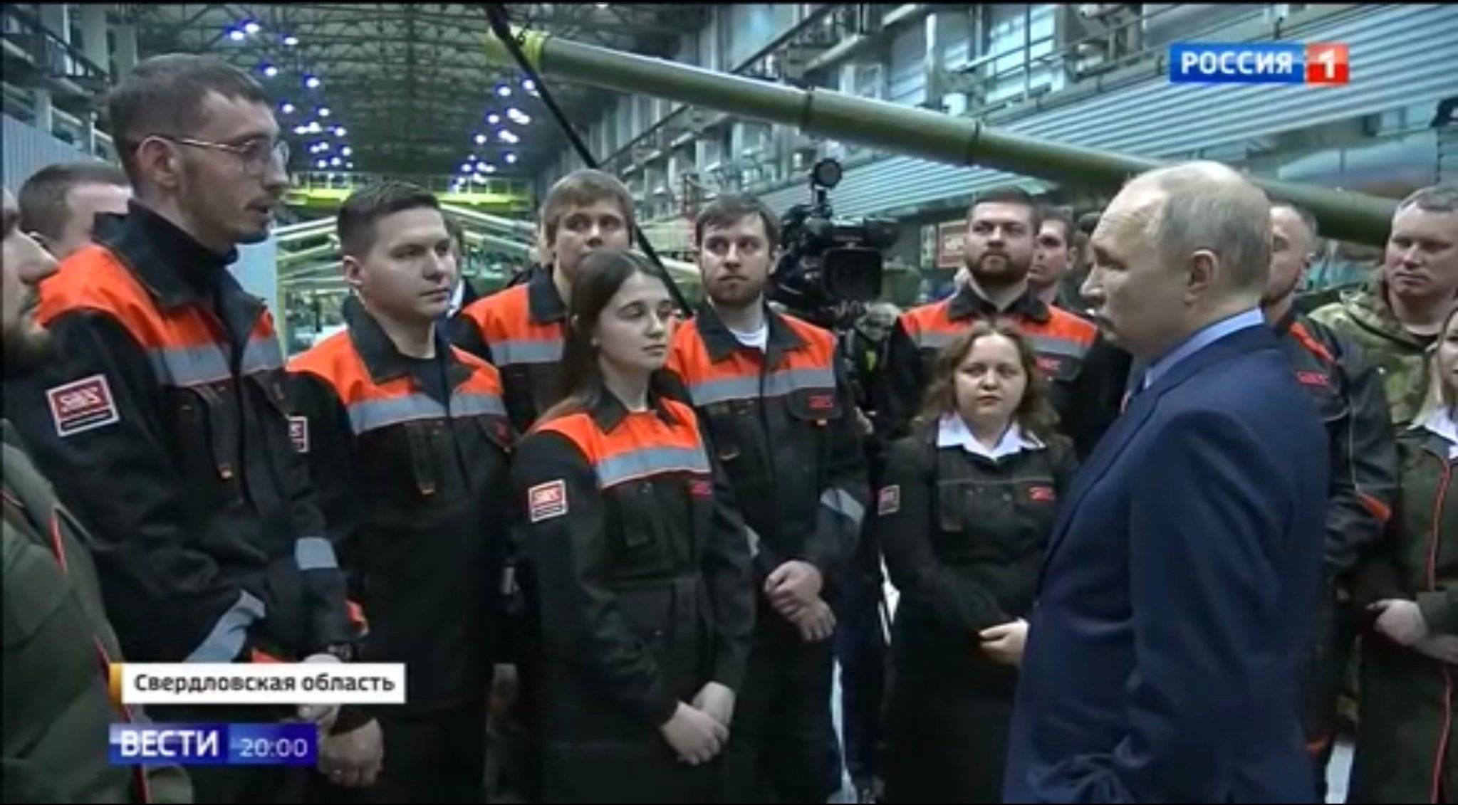Putin rozmawia z młodymi robotnikami na tle czołgów