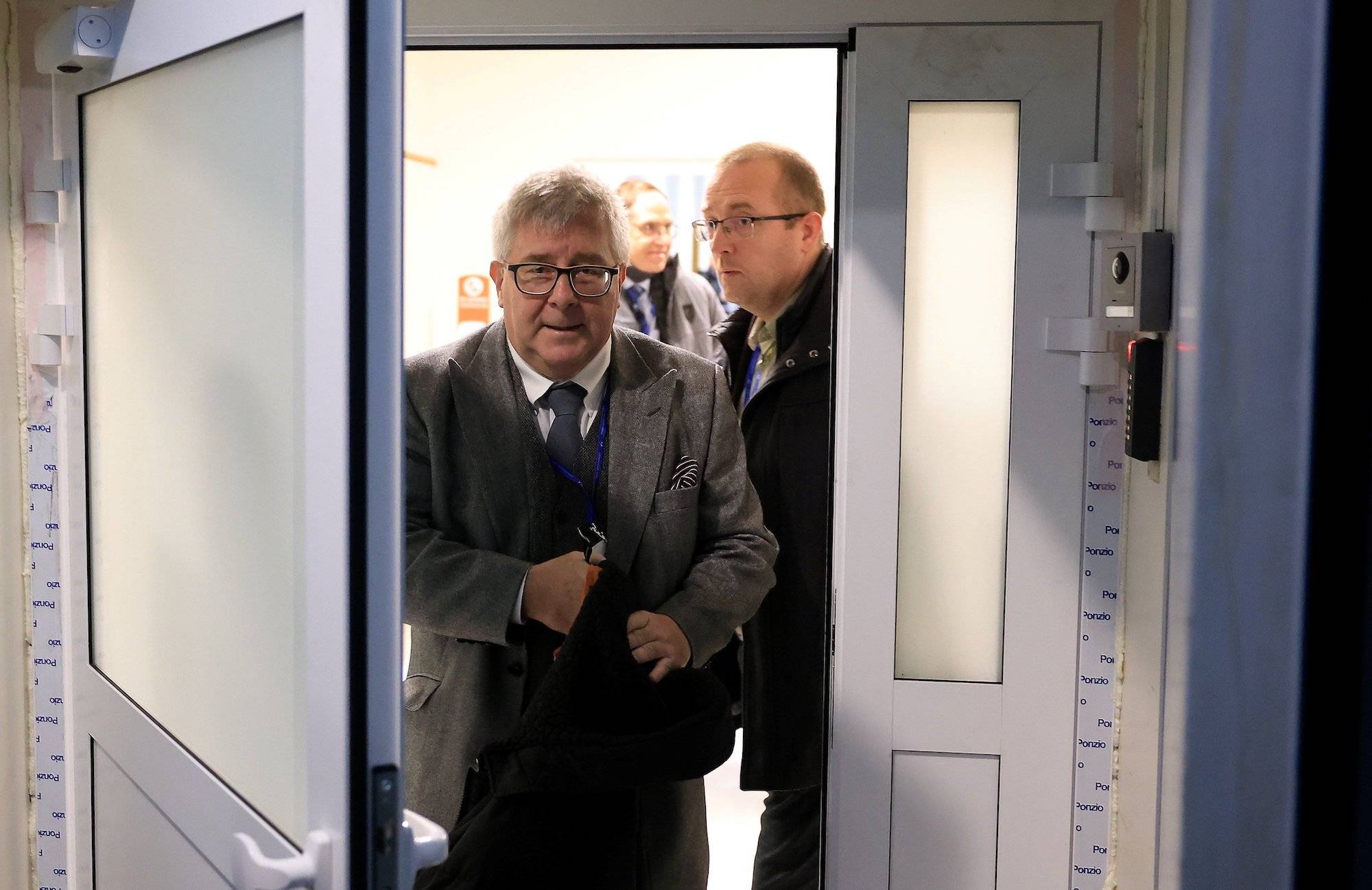 Ryszard Czarnecki w szarym garniturze wychodzi z siedziby PiS przy Nowogrodzkiej. W ręku trzyma płaszcz