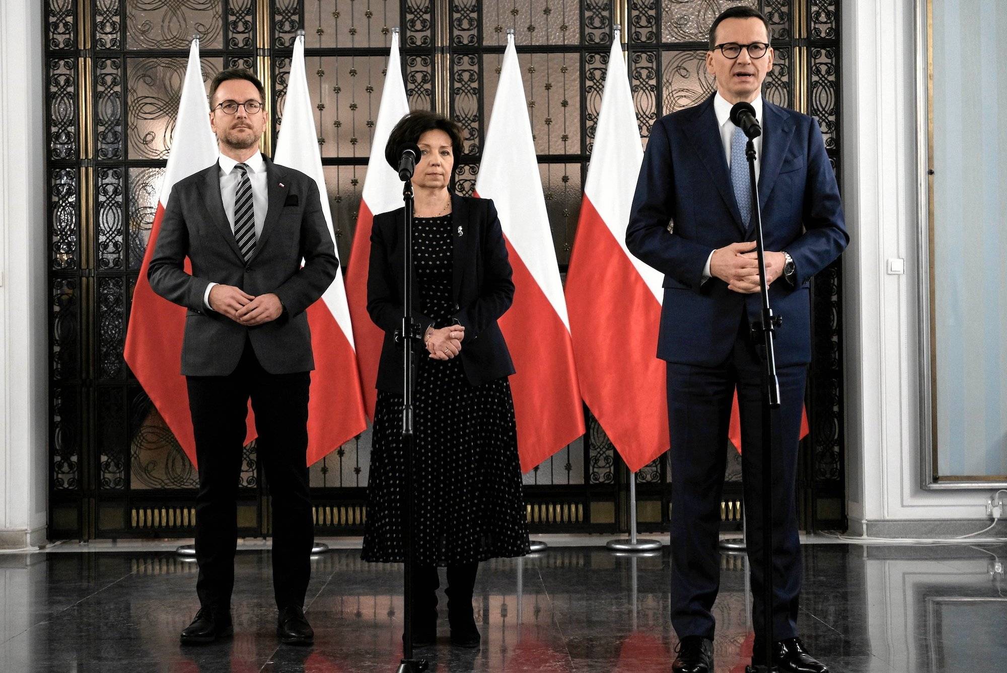 Waldemar Buda, Marlena Maląg i Mateusz Morawiecki na konferencji prasowej na tle biało-czerwonych flag. Przemawia Morawiecki