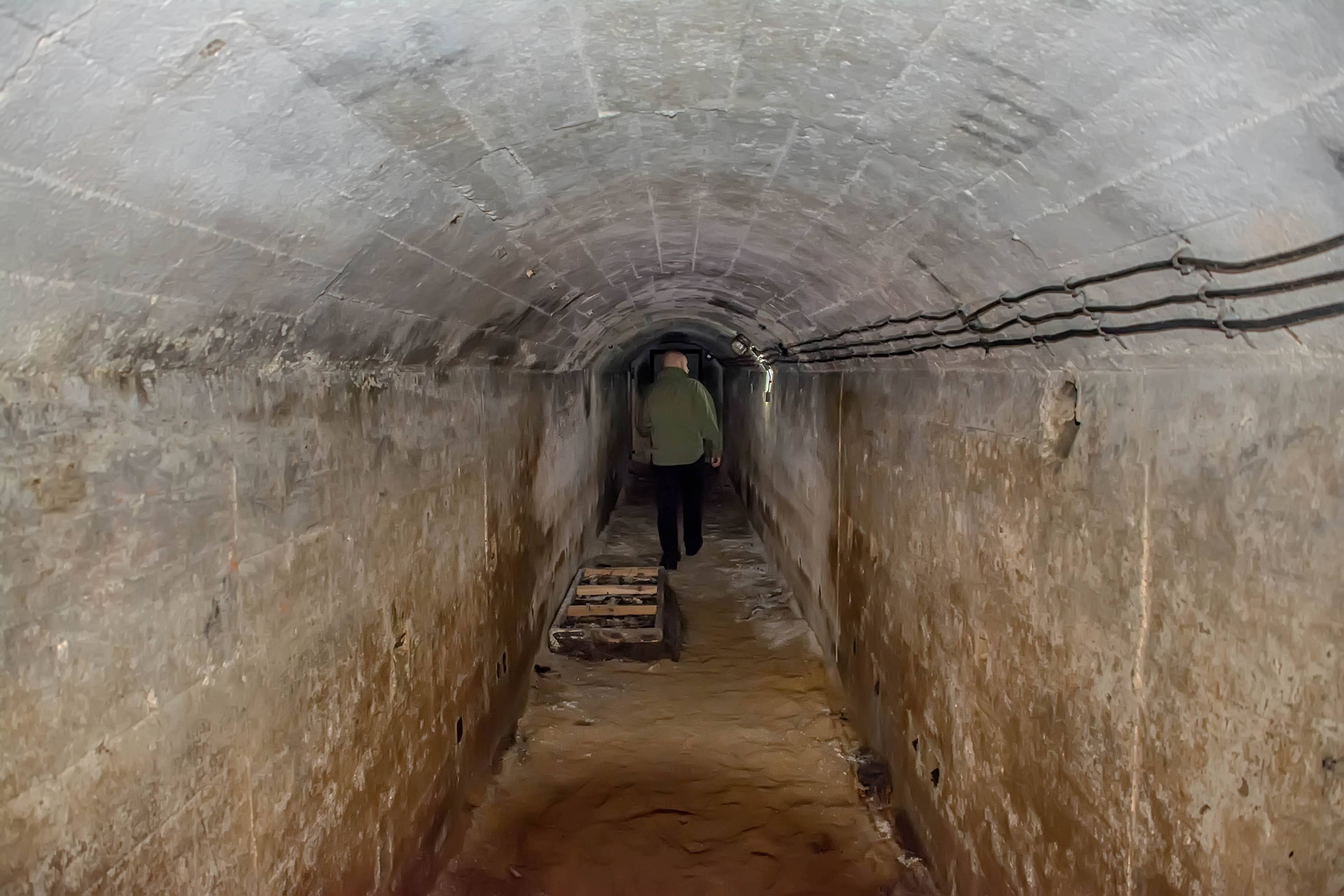 Nioski piwniczny korytarz, widać sylwetkę człowieka idącego korytarzem