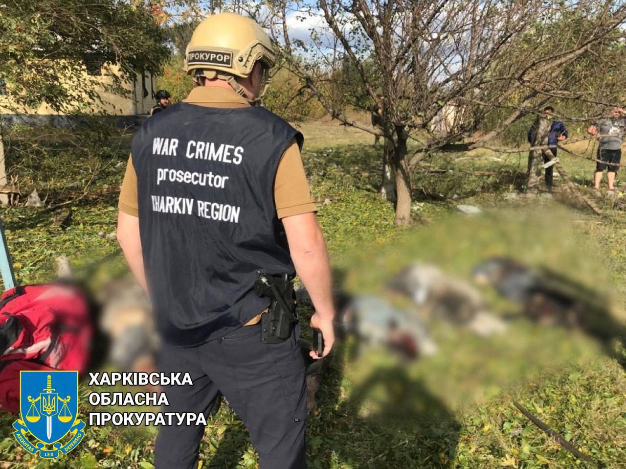 Mężczyzna w hełmie z napisem w j. ukraińskim prokurator stoi nad ciałami cywilnych ofiar bombardowania. Rosyjskie zbrodnie wojenne