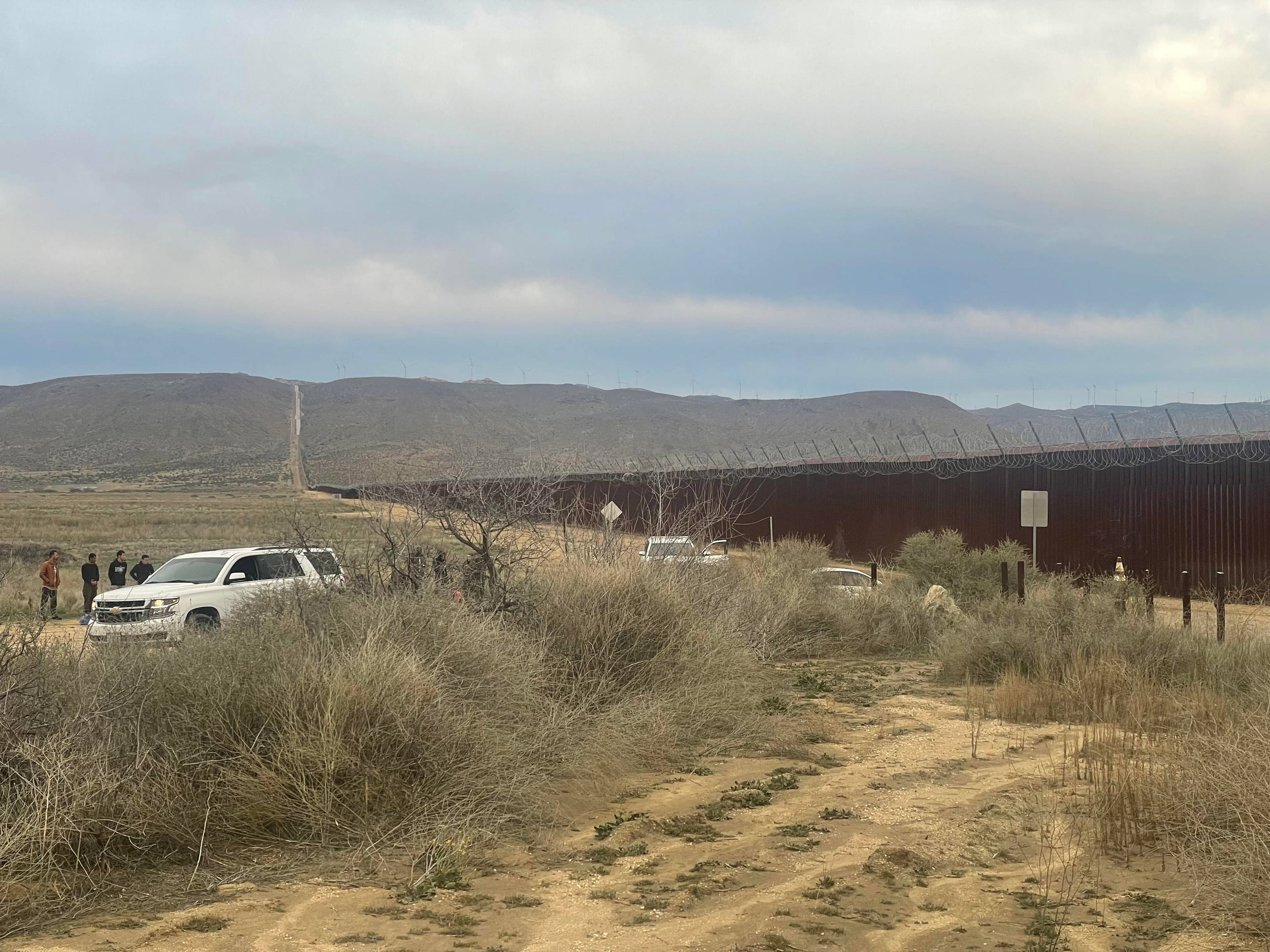 czterech mężczyzn przy furgonetce przy murze granicznym