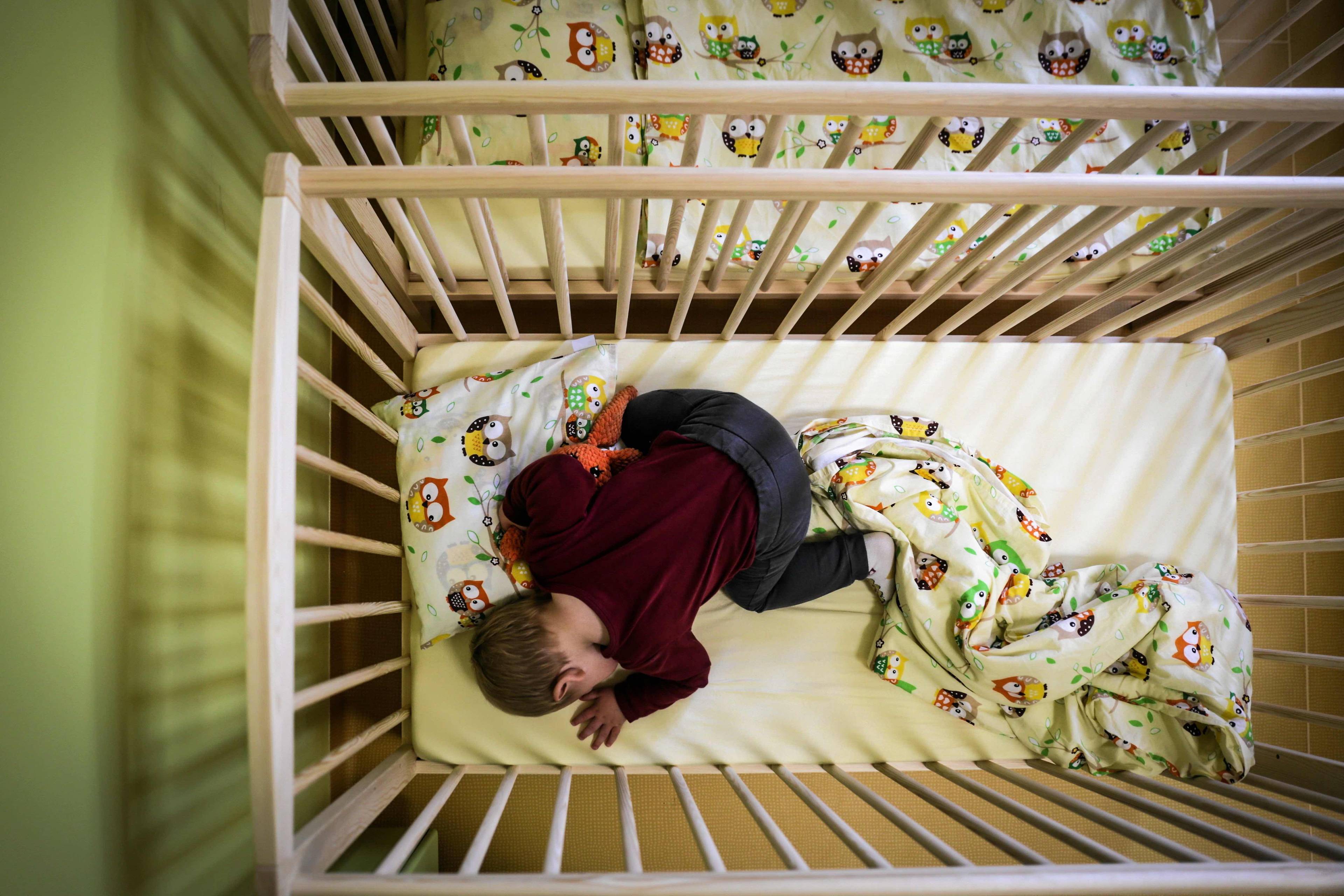 Dziecko śpi w łóżeczku w żłobku. Praca kobiet