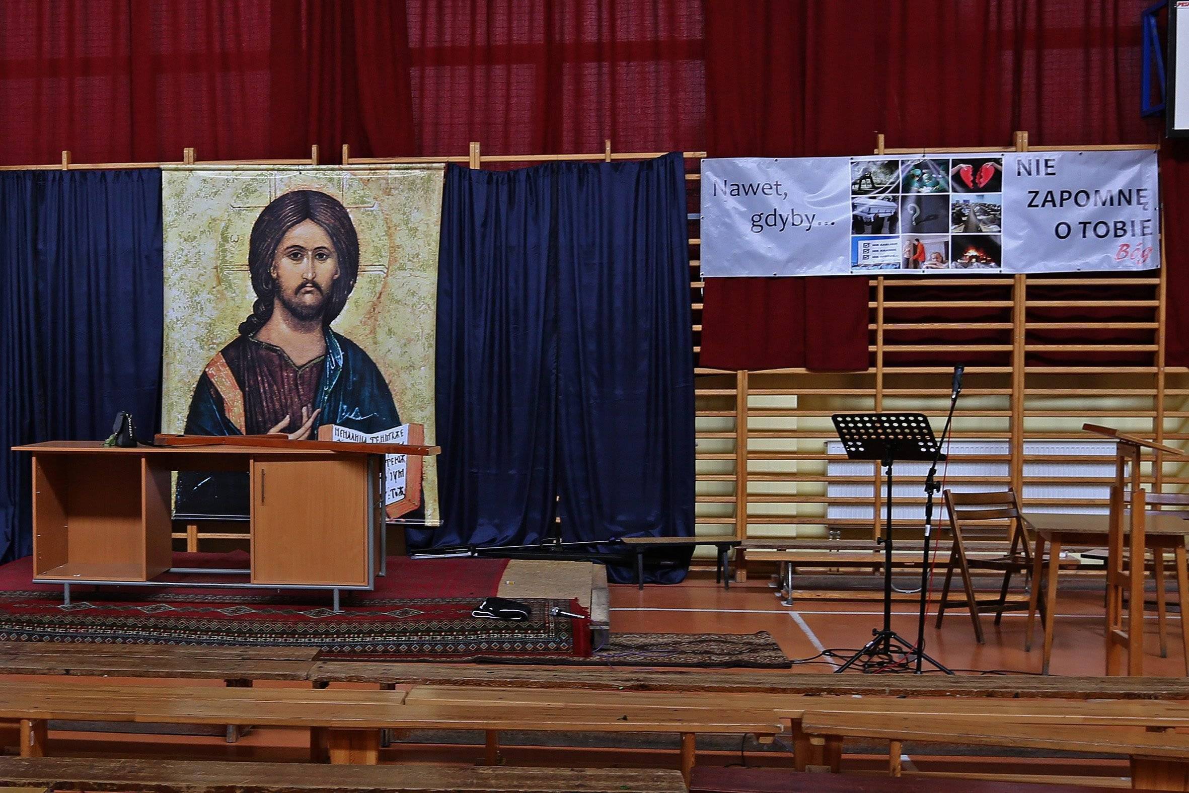 Duży plakat z postacią Jezusa zawieszony na drabinkach w szkolnej sali gimnastycznej