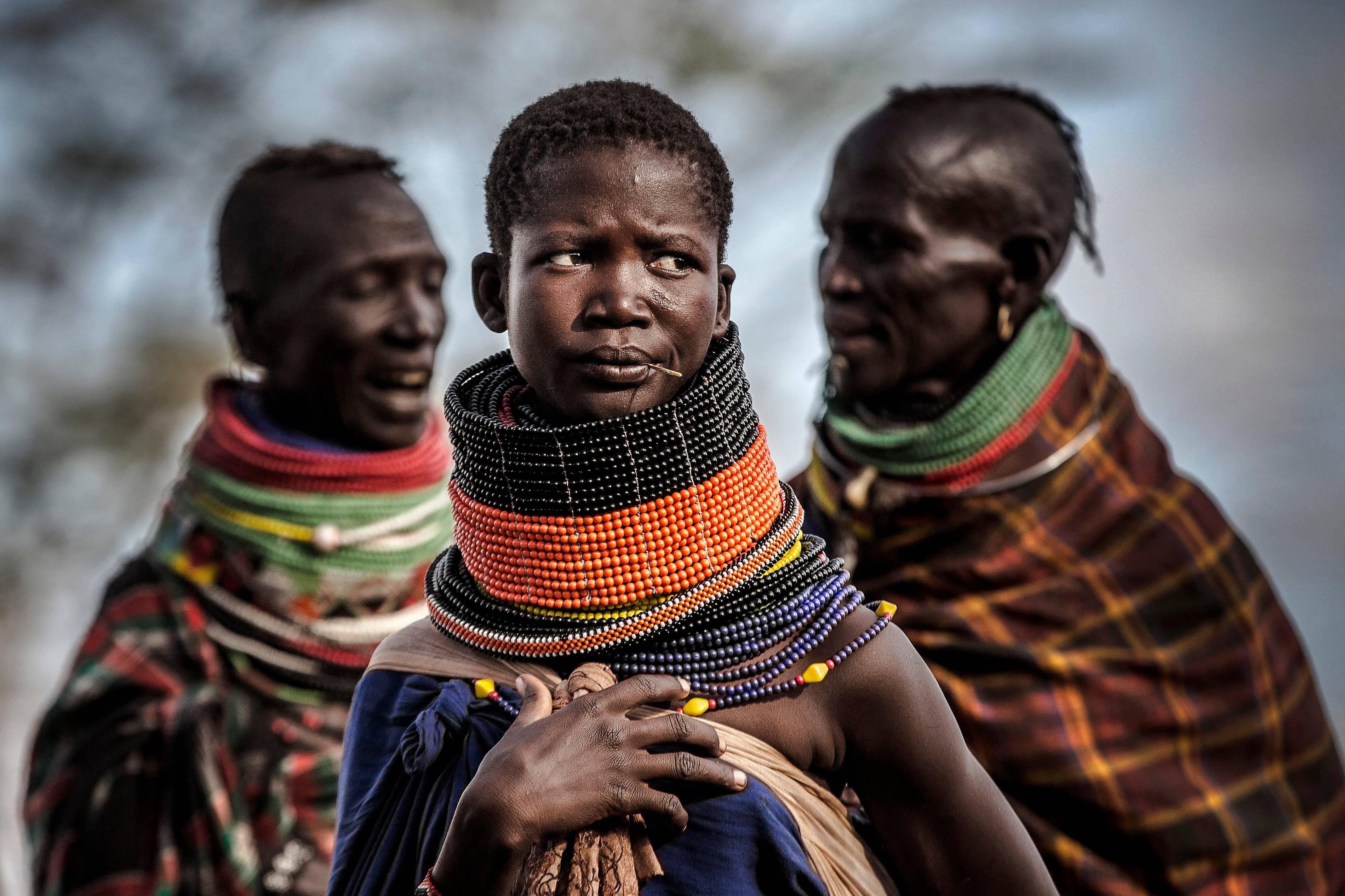 Women belonging to the Turkana community gather next to their village in an arid dry area in Morungole, Turkana County, Kenya, on October 7, 2019. Turkana is a vast, dry area in the north-west of Kenya that is on the frontline of climate change. With regular searing temperatures the Turkana people are suffering from recurring and prolonged droughts. (Photo by Luis TATO / AFP)