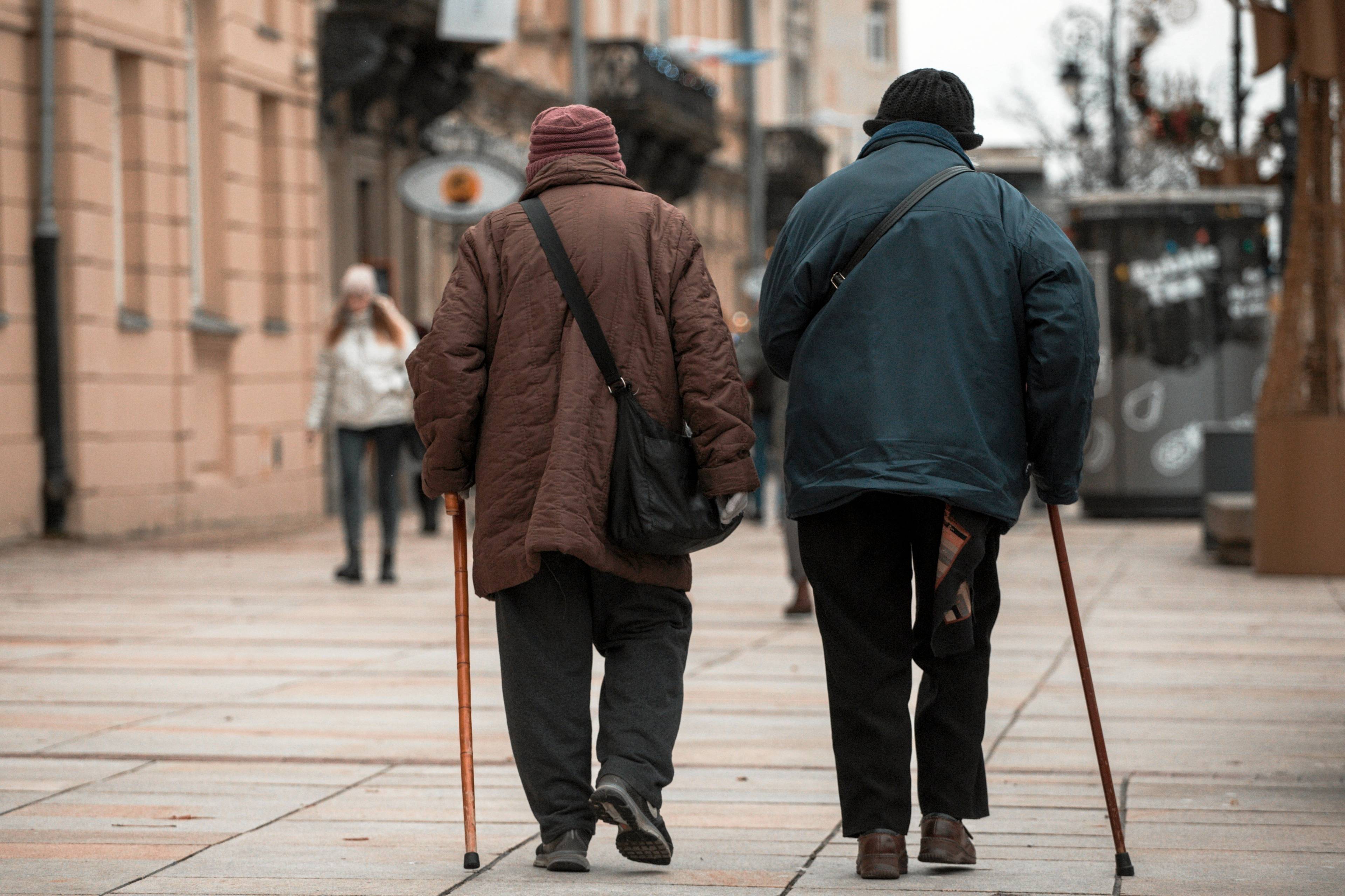 Para starszych osób idzie chodnikiem