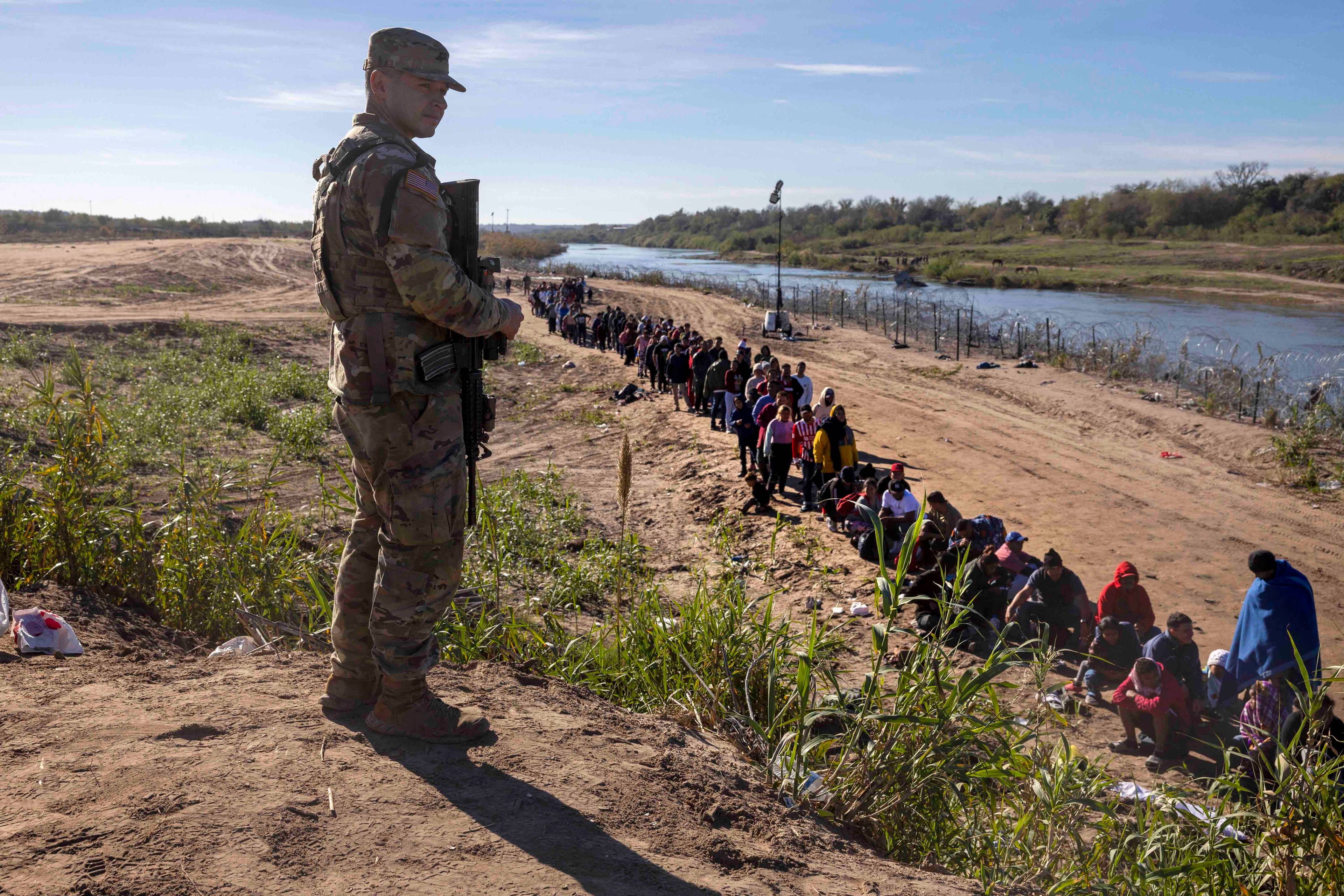 Strażnik grabiczny patrzy na osoby przekraczające granicę USA z Meksykiem