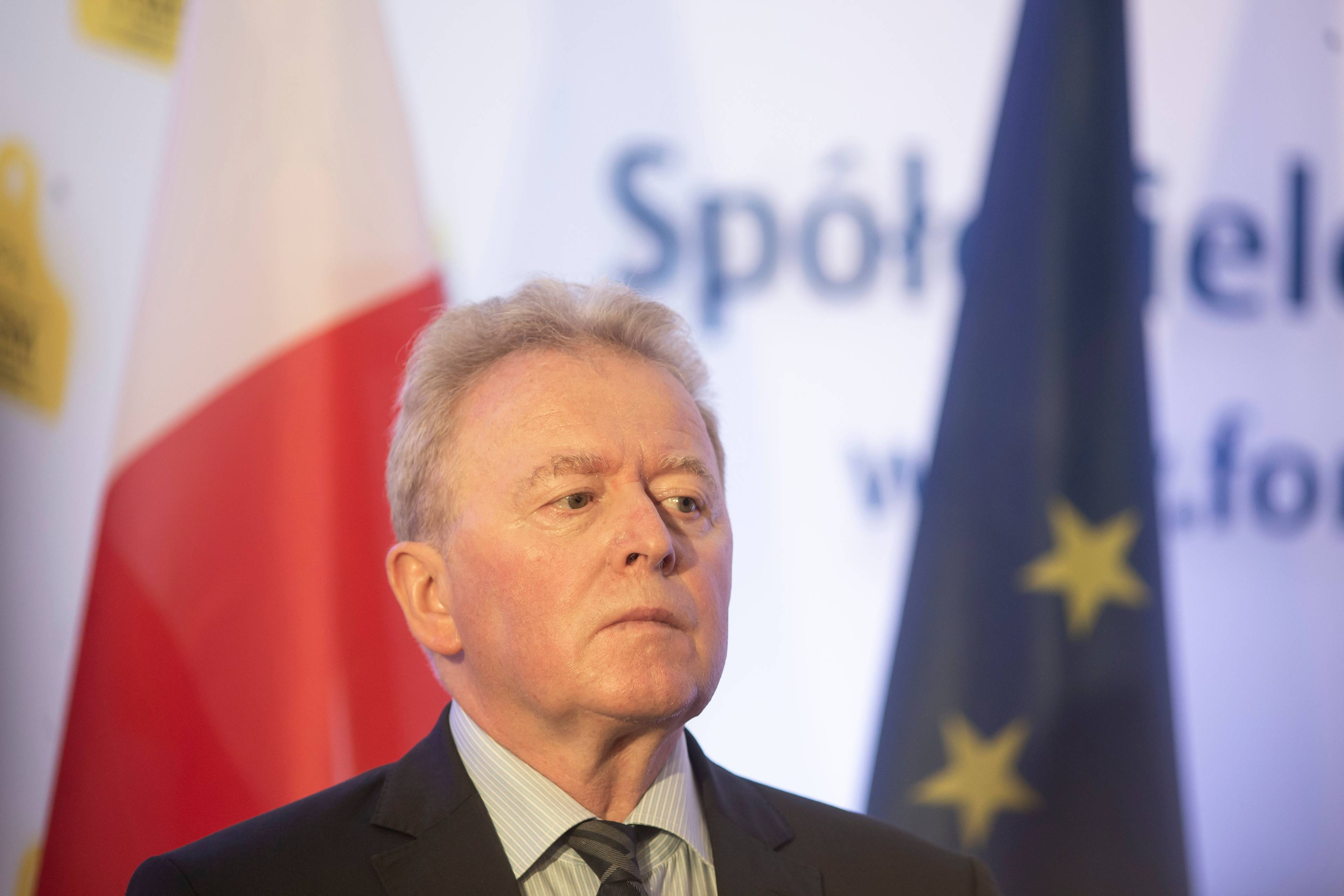 Komisarz rolnictwa Janusz Wojciechowski na tle flag polski u Unii Europejskiej