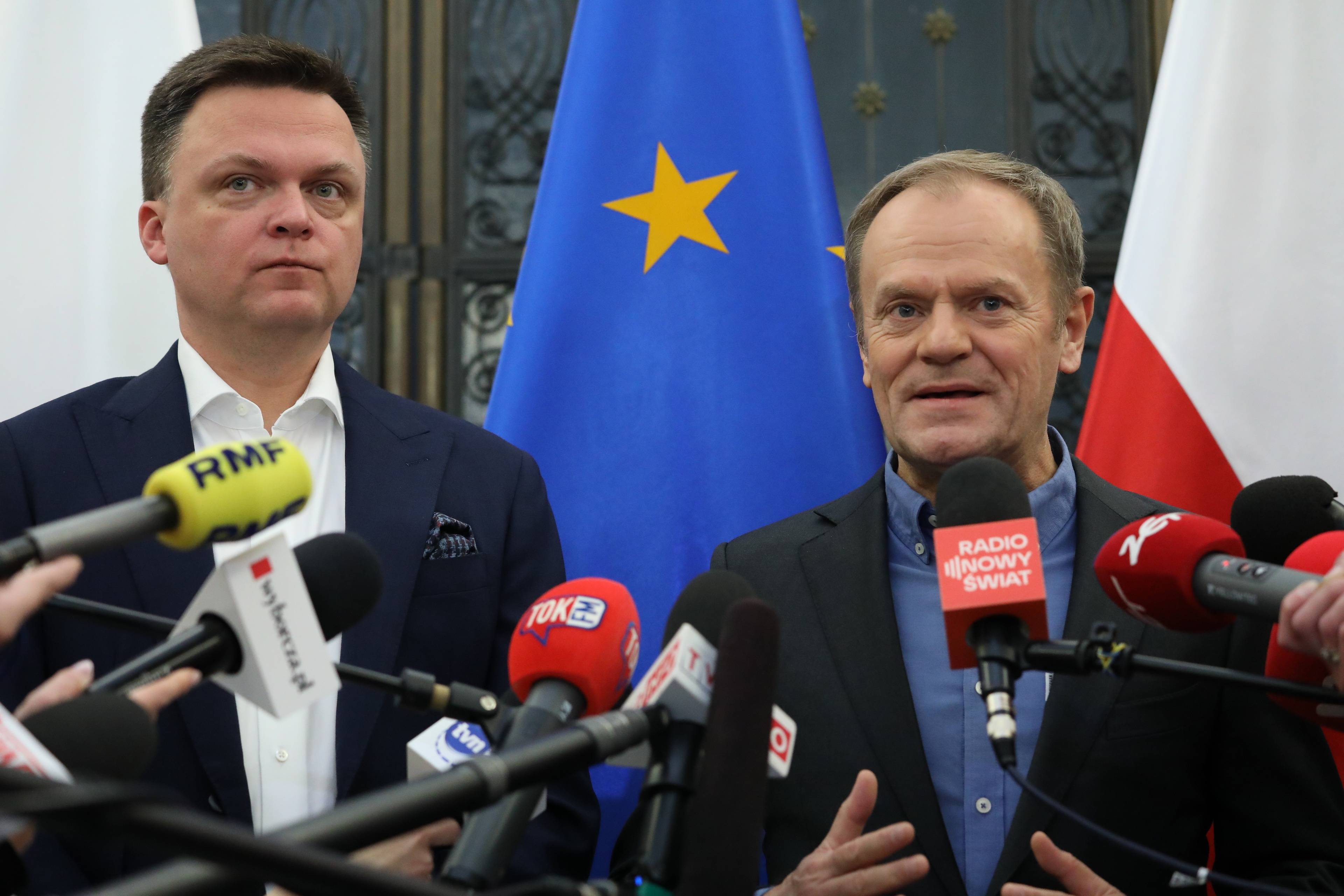Tusk i Hołownia na tle polskich i europejskich flag