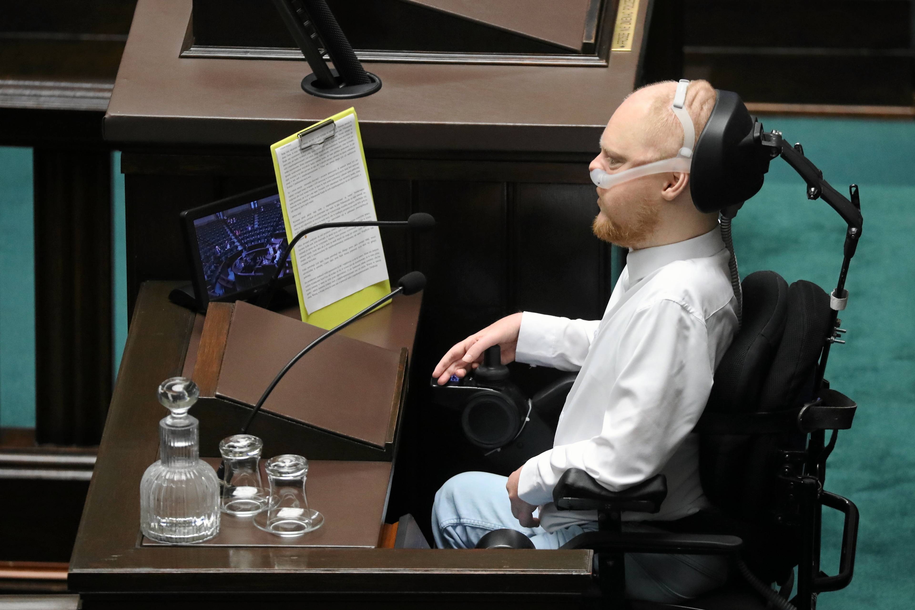 Mężczyzna na wózku inwalidzkim przy mikrofonie na mównicy sejmowej