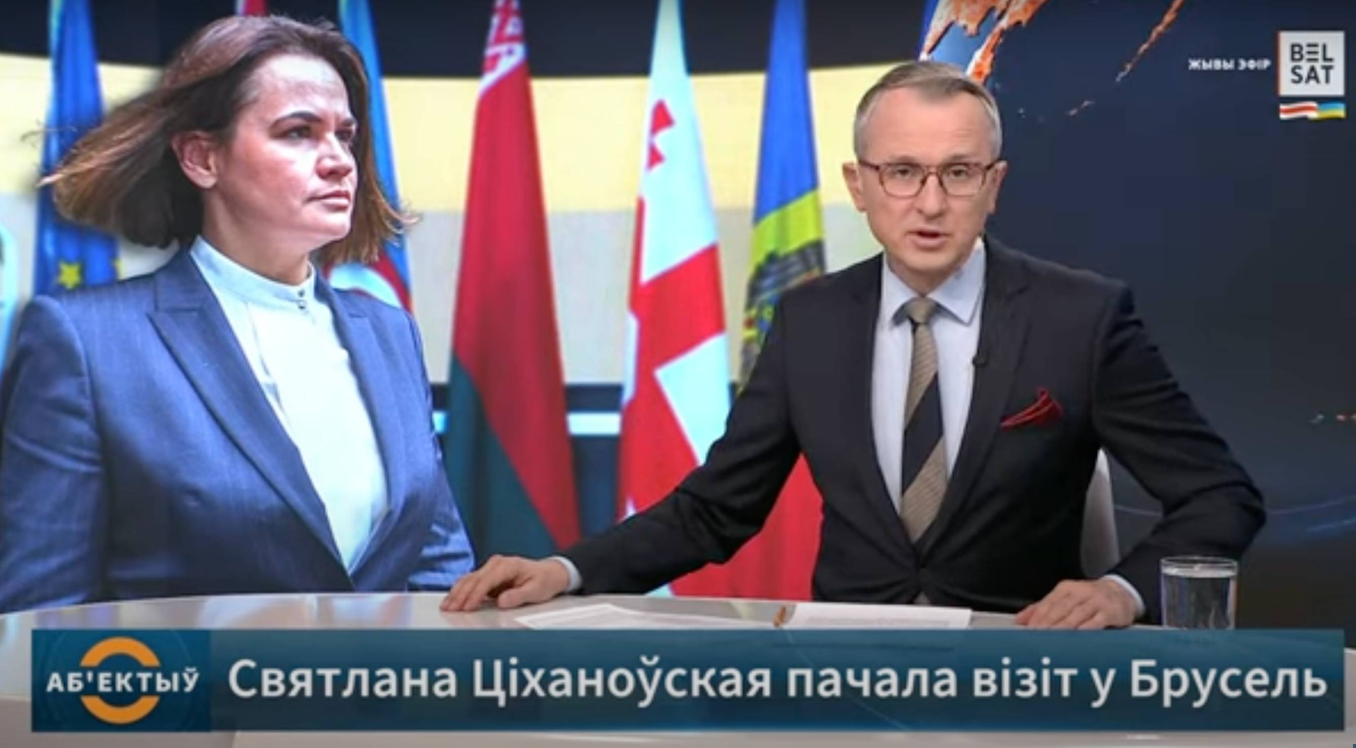 Studio telewizji Biełsat, prowadzący program dziennikarz czyta informacje, w tle zdjęcie Swietlany Cichanouskiej. Biełsat
