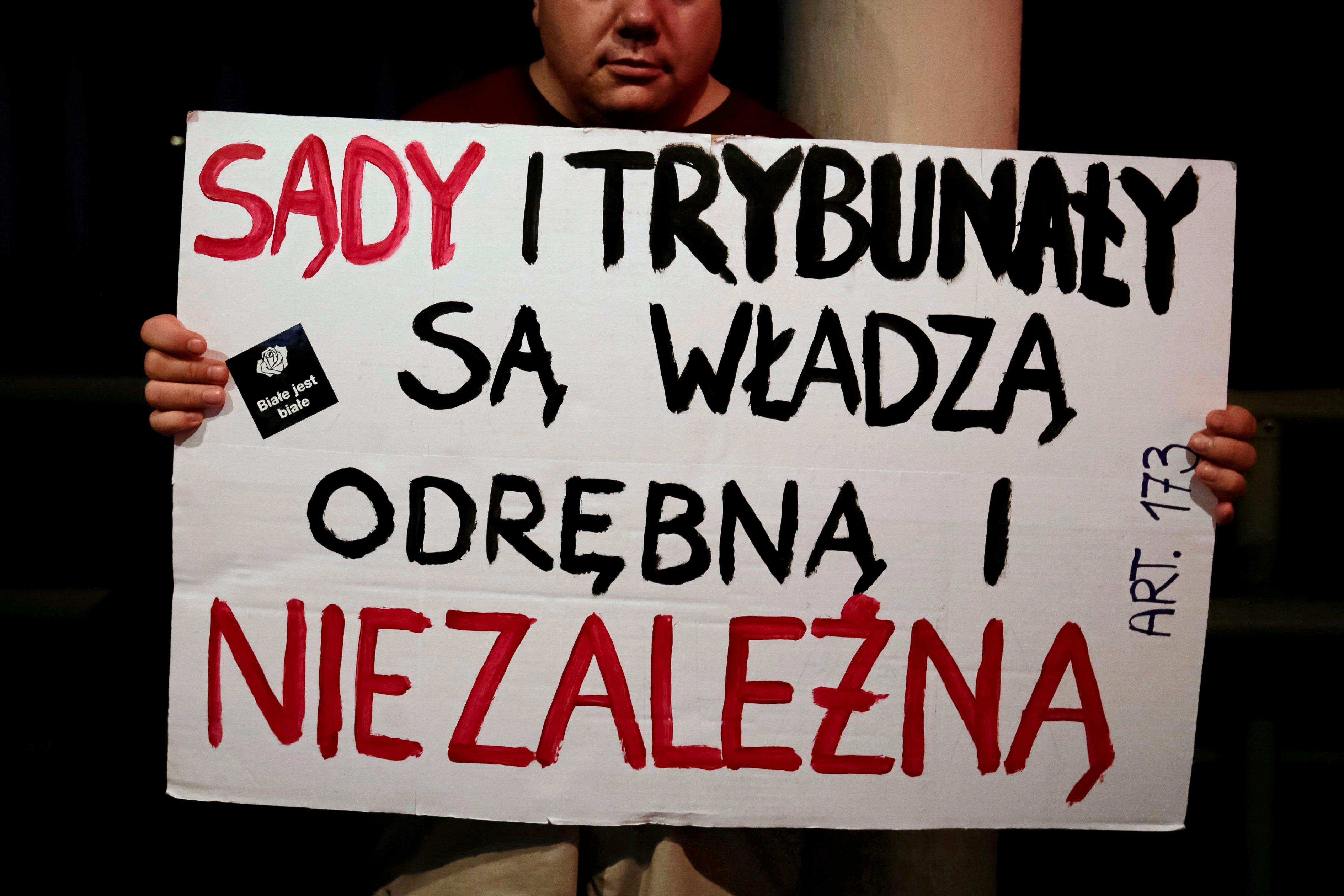 Mężczyzna trzyma plakat "Sądy i trybubały są władzą odrębną i niezależną"