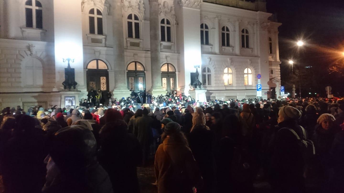 Demonstranci zgromadzeni przed gmachem Zachęty, wieczór, fasada gmachu mocno oświetlona