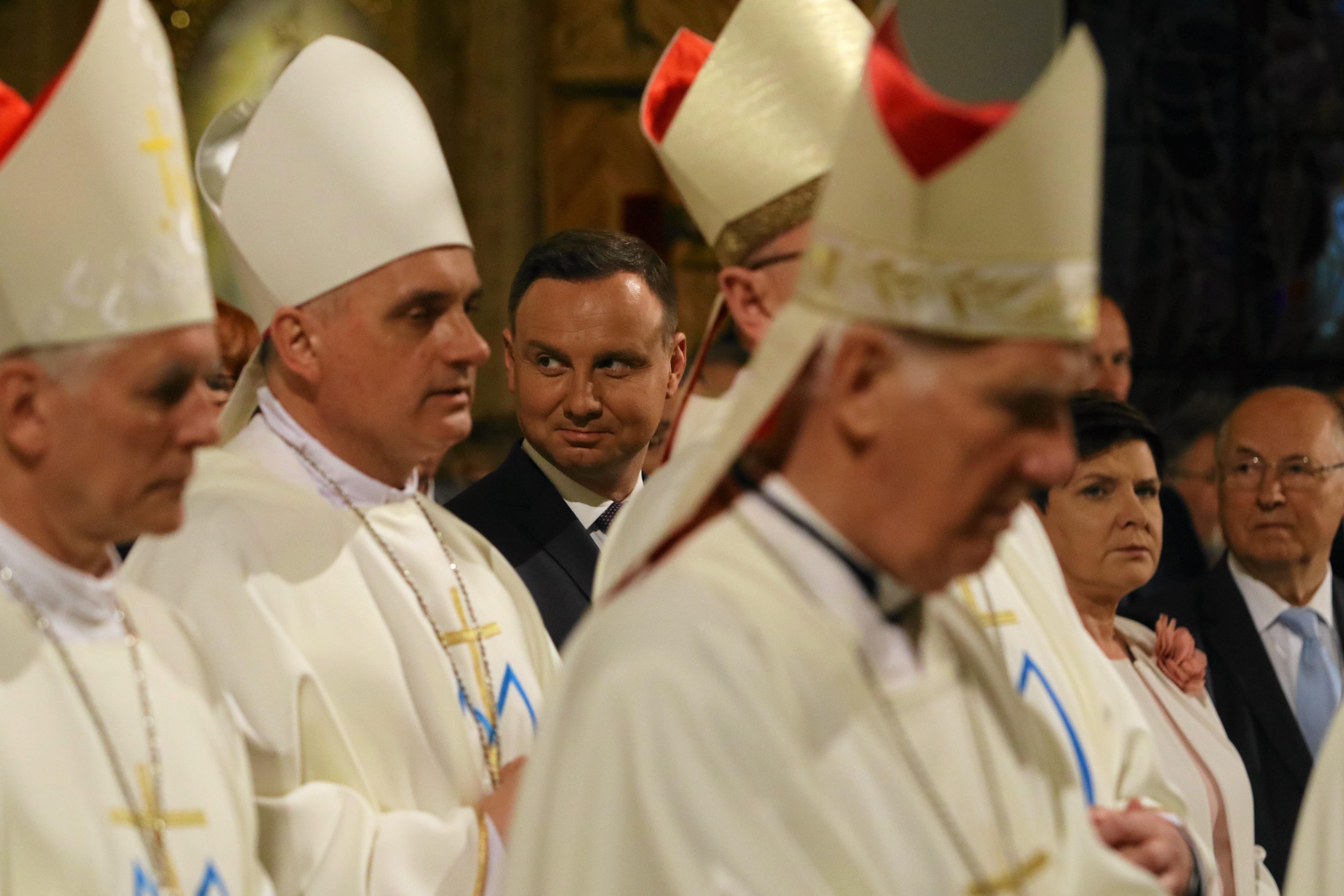 Andrzej Duda wsród biskupów ubranych w białe szaty liturgiczne