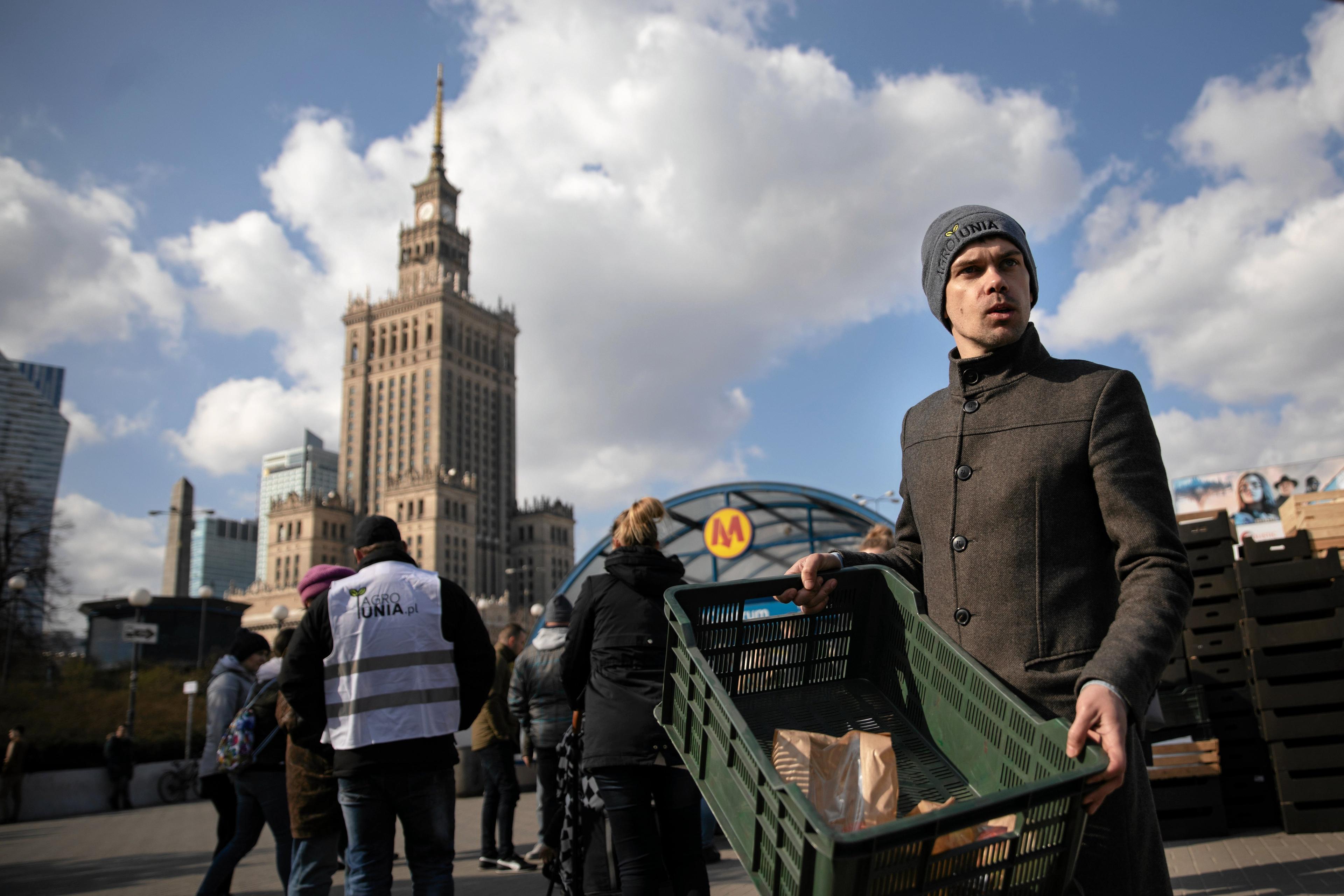 Michał Kołodziejczak, lider AgroUnii, trzyma skrzynkę z jabłkami podczas protestu w Warszawie przy metrze Centrum