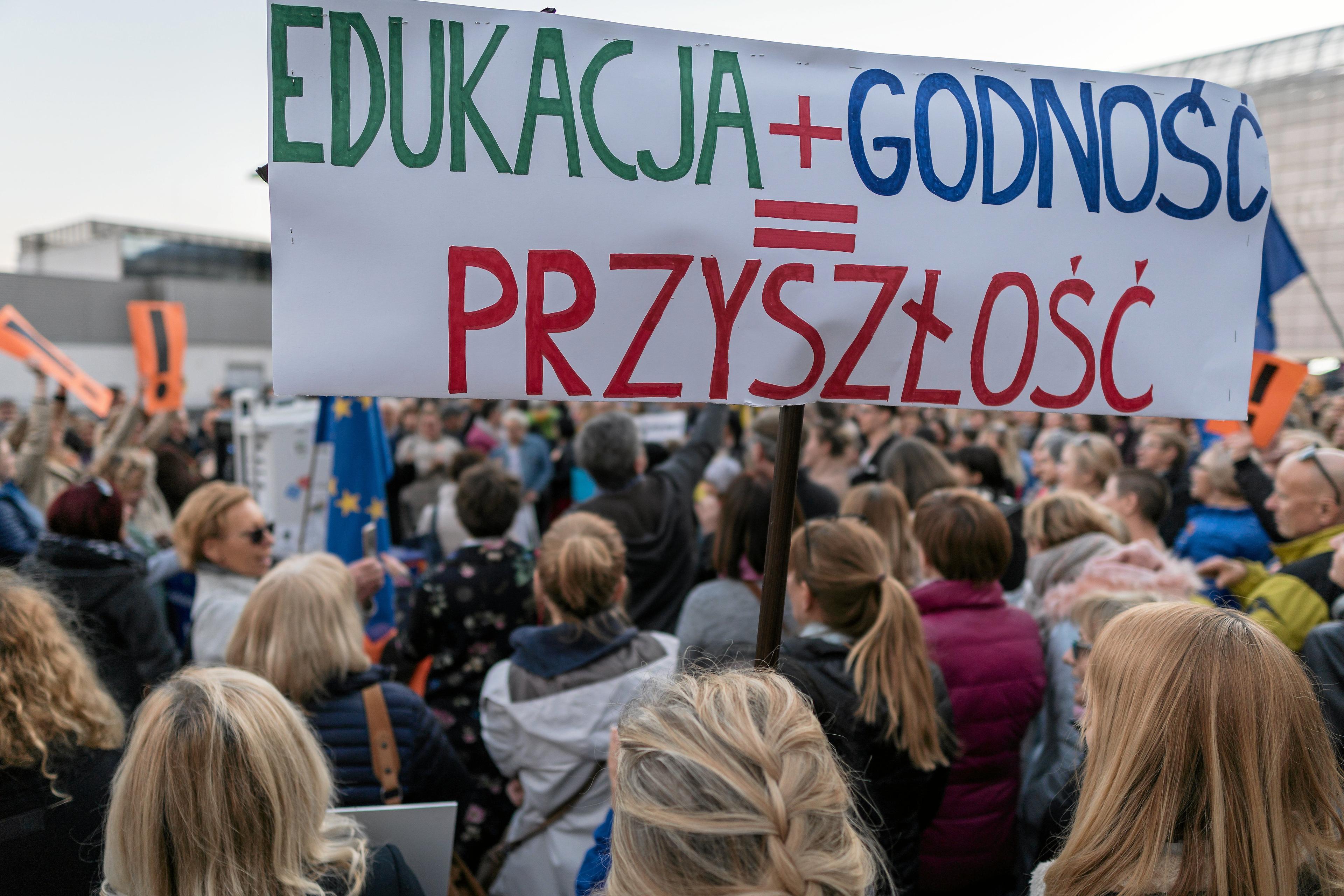 Nauczciele protestują z transparentem "Edukacja+Godność=Przyszłość"