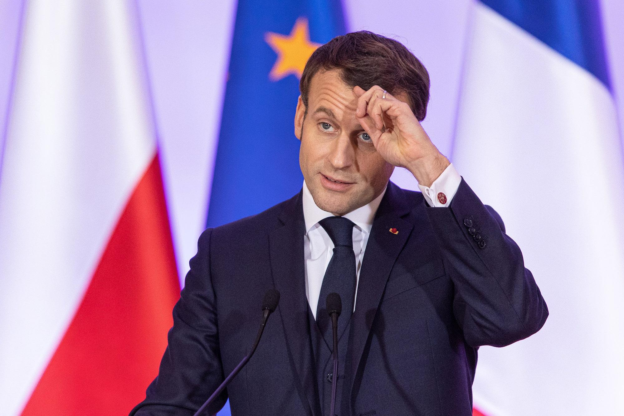 Prezydent Francji Emmanuel Macron na tle polskiej i unijnej flagi