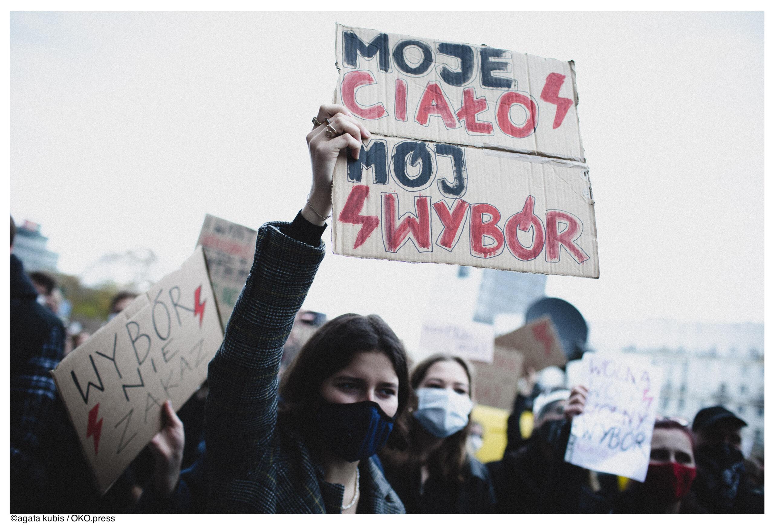 Kobieta trzyma nad głową baner z napisem Moje ciało, mój wybór