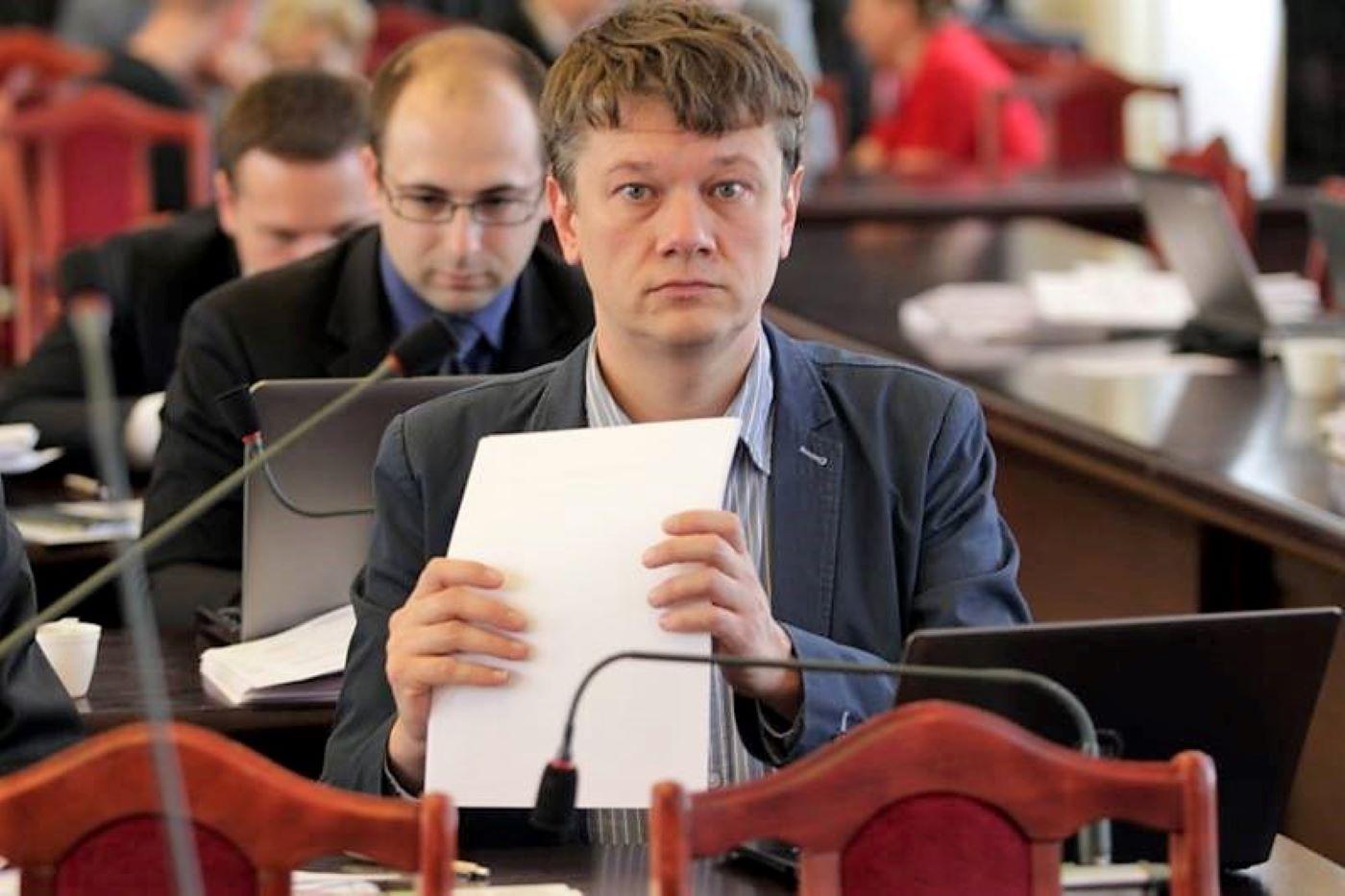 Radny Dyba-Bojarski podczas sesji rady, w ręku trzyma plik kartek