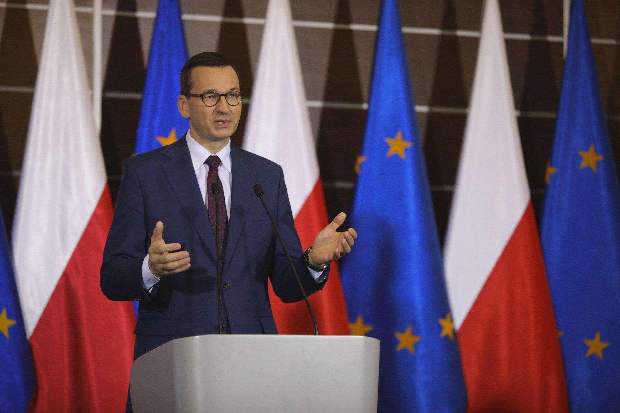 Premier Mateusz Morawiecki na tle polskich i europejskich flag
