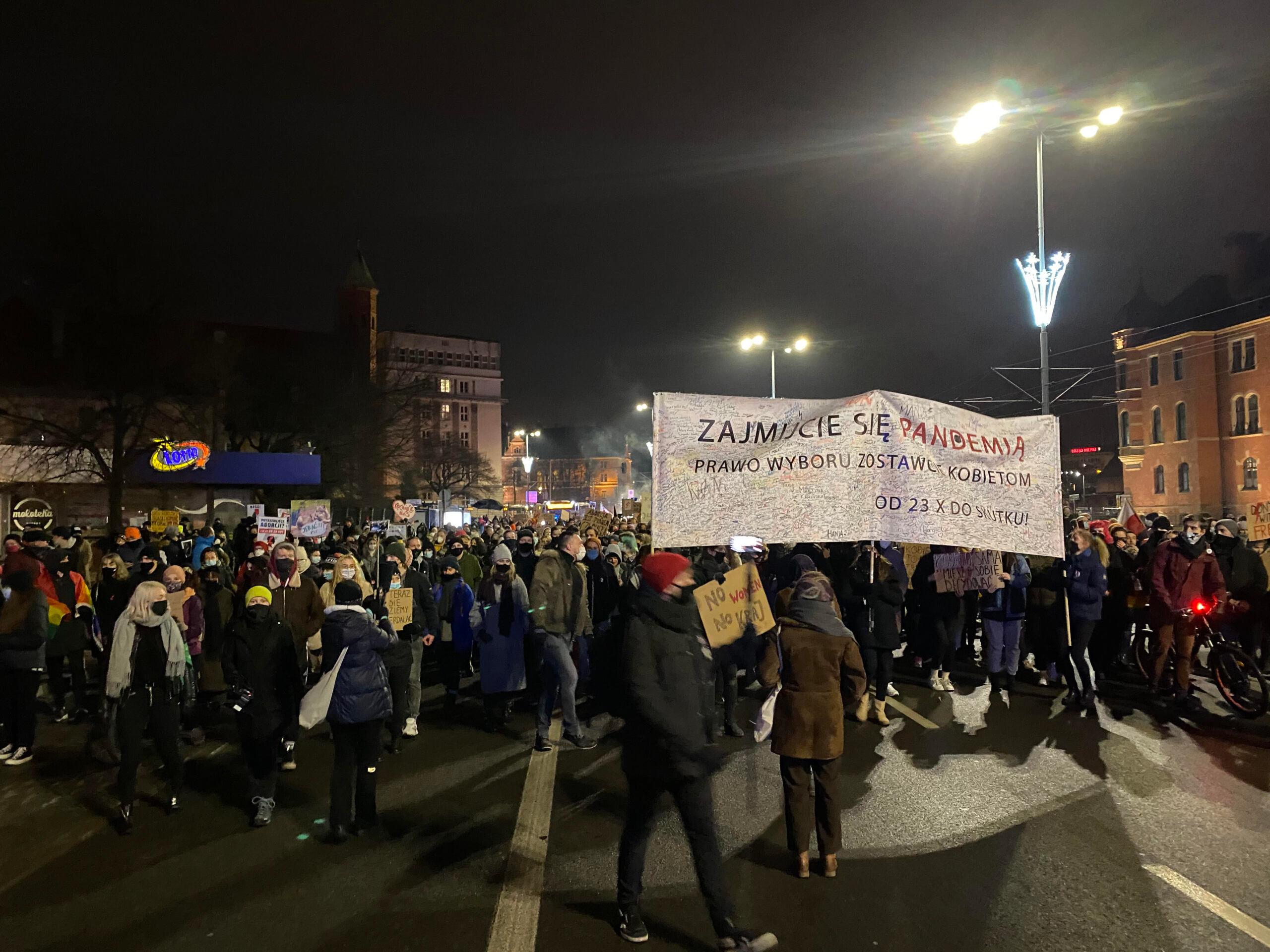 Ludzie na demonstracji, widać transparent "Zajmijcie sie pandemia, wybór zosrawcie kobietom"