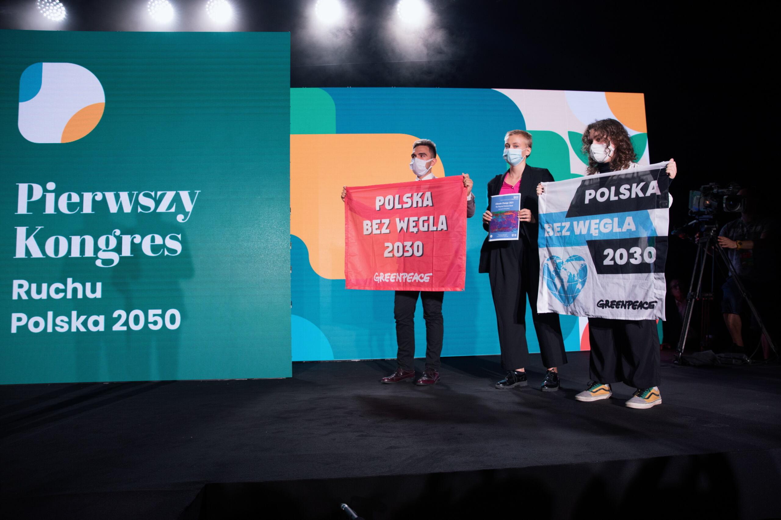 aktywiści Greenpeace trzymają tablicę z postulatami odejścia od węgla do 2030 roku na scenie kongresu ruchu Polska 2050