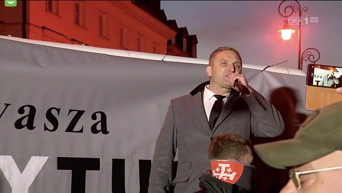 Robert Bąkiewicz, prezes Stowarzyszenia Marsz Niepodległości, podczas kontrmanifestacji wobec proeuropejskiej manifestacji na Placu Zamkowym. Mówi: "Volksdeutsche was prowadzą", źródło: Wiadomości TVP, 11 października 2021