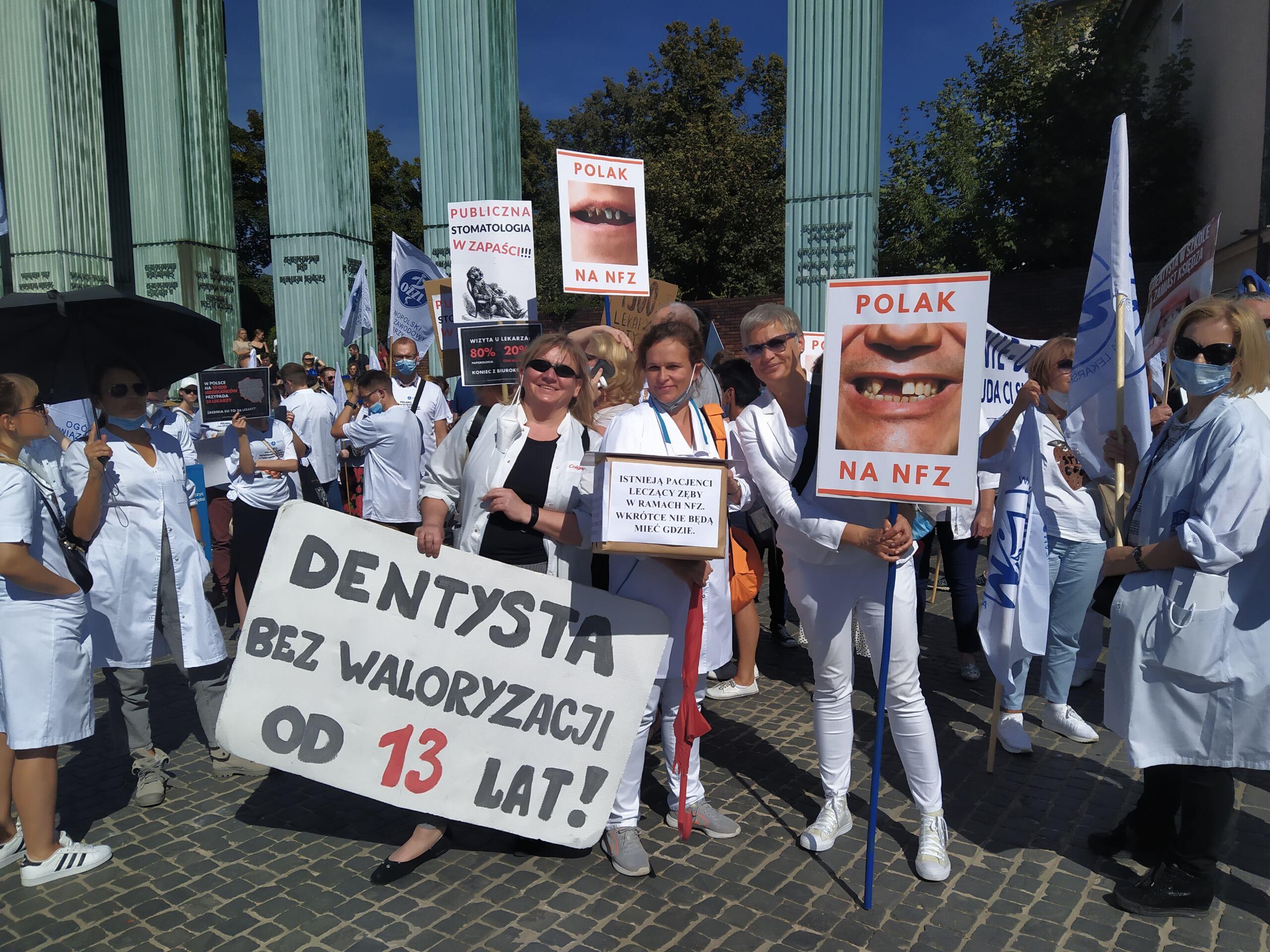 Lekarze dentyści trzymają transparent z napisem "Dentysta bez waloryzacji od 13 lat"