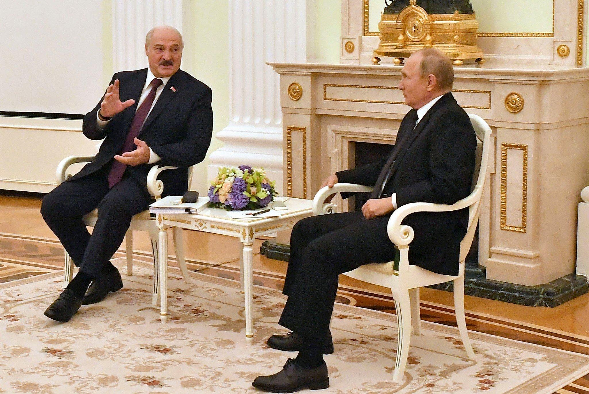 Putin i Łukaszenka siedzą na białych krzesłach i gestykulują