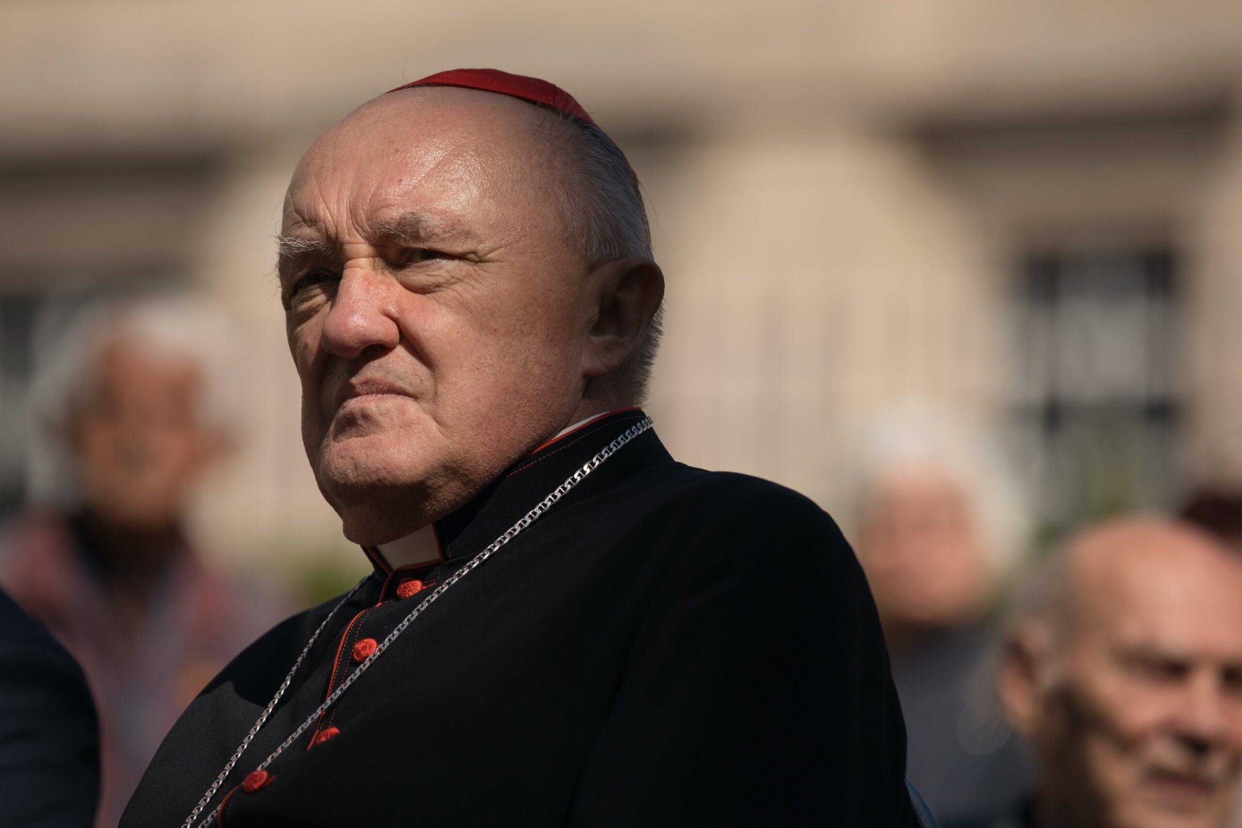Oślepiony światłem kardynał Kazimierz Nycz mruży oczy.