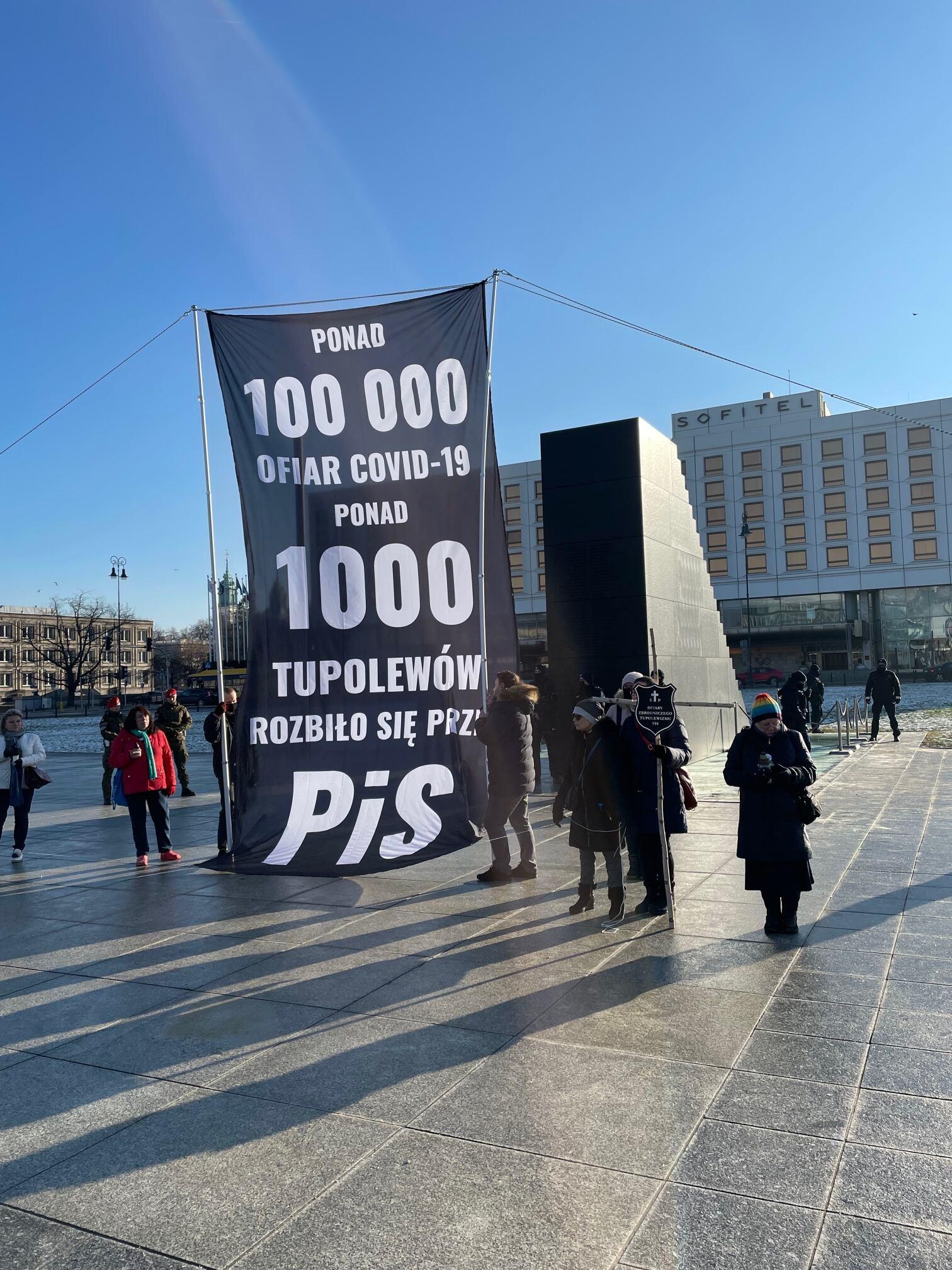 Transparent z napisem "Ponad 100000 ofiar Covid-19, ponad 1000 tupolewów rozbło sie przez PiS" przed pomnikiem smoleńskim w Warszawie