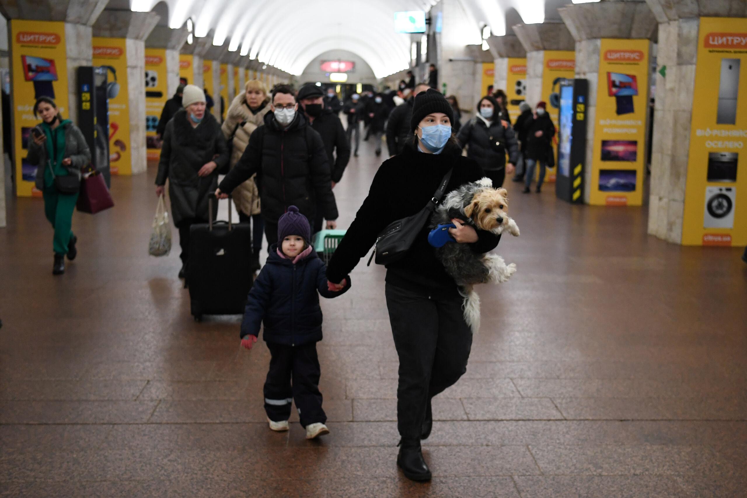 A woman with a child and a dog walks at a metro station in Kyiv early on February 24, 2022. - Russian President Vladimir Putin announced a military operation in Ukraine on Thursday with explosions heard soon after across the country and its foreign minister warning a "full-scale invasion" was underway. (Photo by Daniel LEAL / AFP)