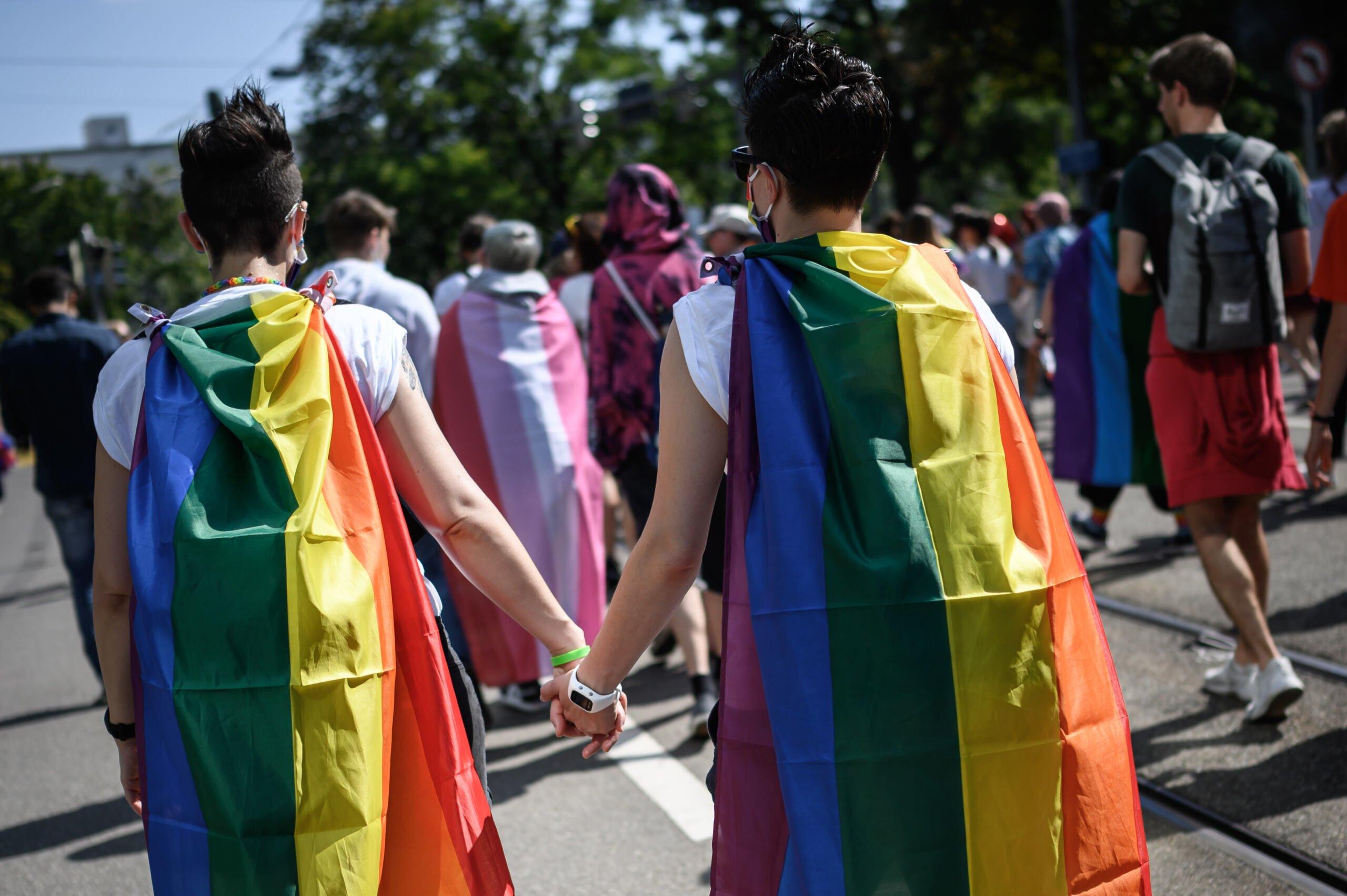 Para lesbijek z tęczowymi flagami na paradzie równości w Szwajcarii