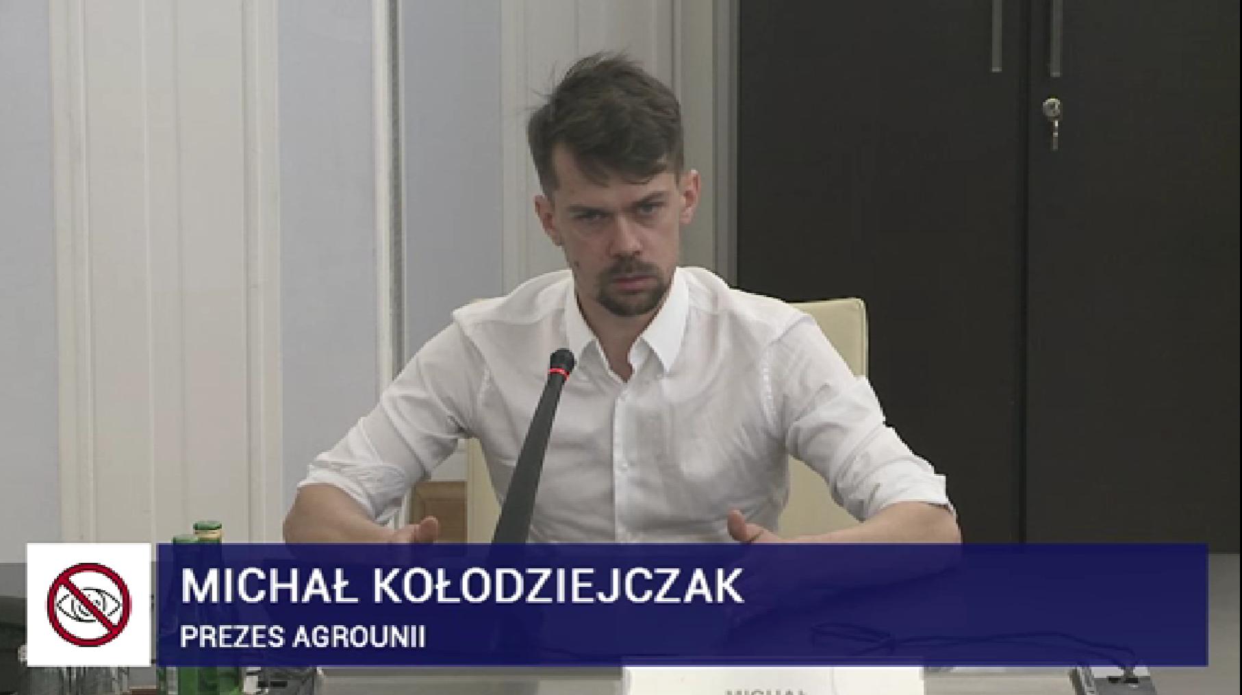 Michał Kołodziejczak w białej koszuli mówi do mikrofonu