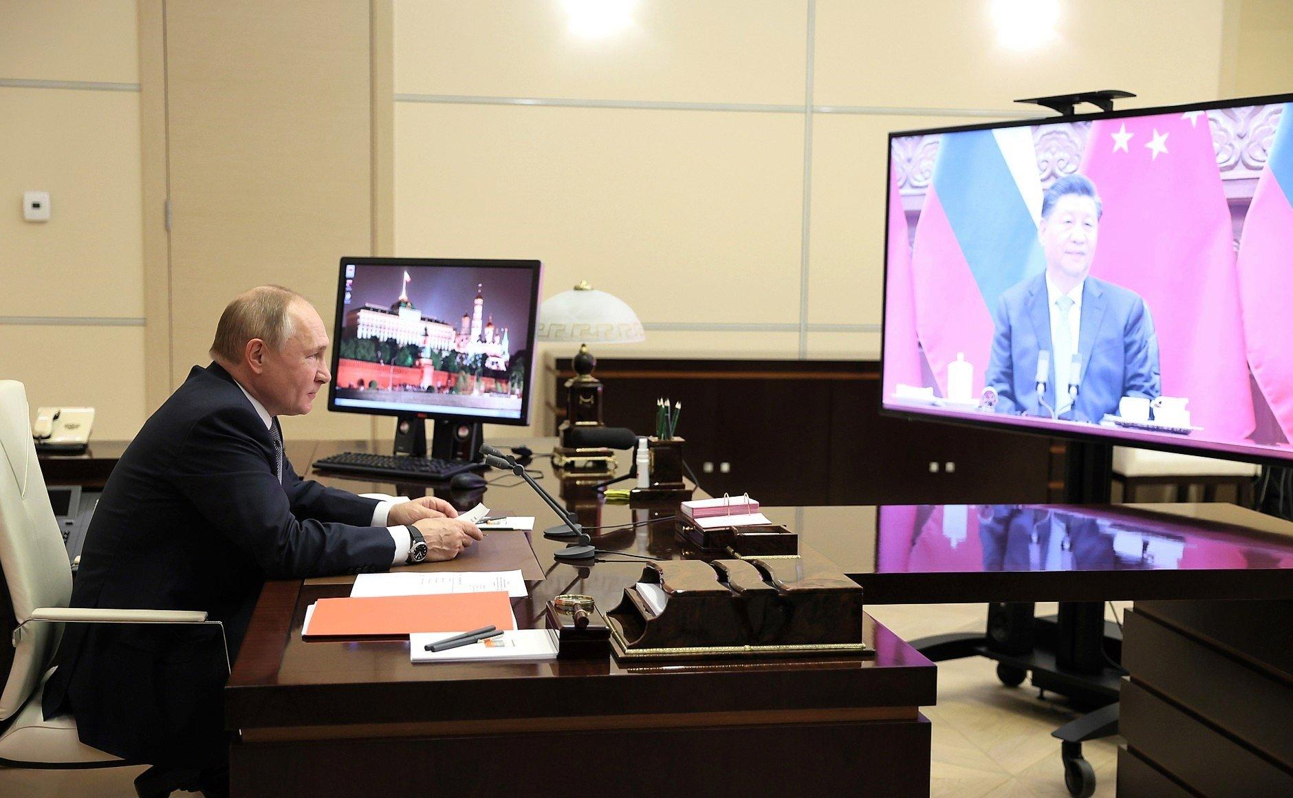 Putin siedzi w swoim gabinecie, na wielkim ekranie przed nim Xi Jinping
