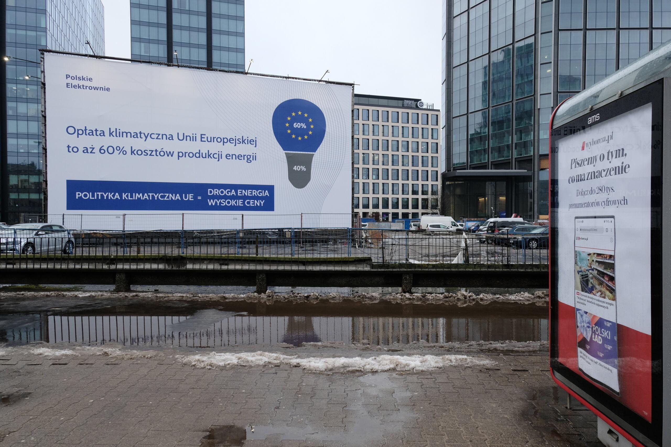 Biały baner z niebieską żarówką z namalowanymi na niej unijnymi gwiazdkami oskarżający UE o wzrost cen prądu