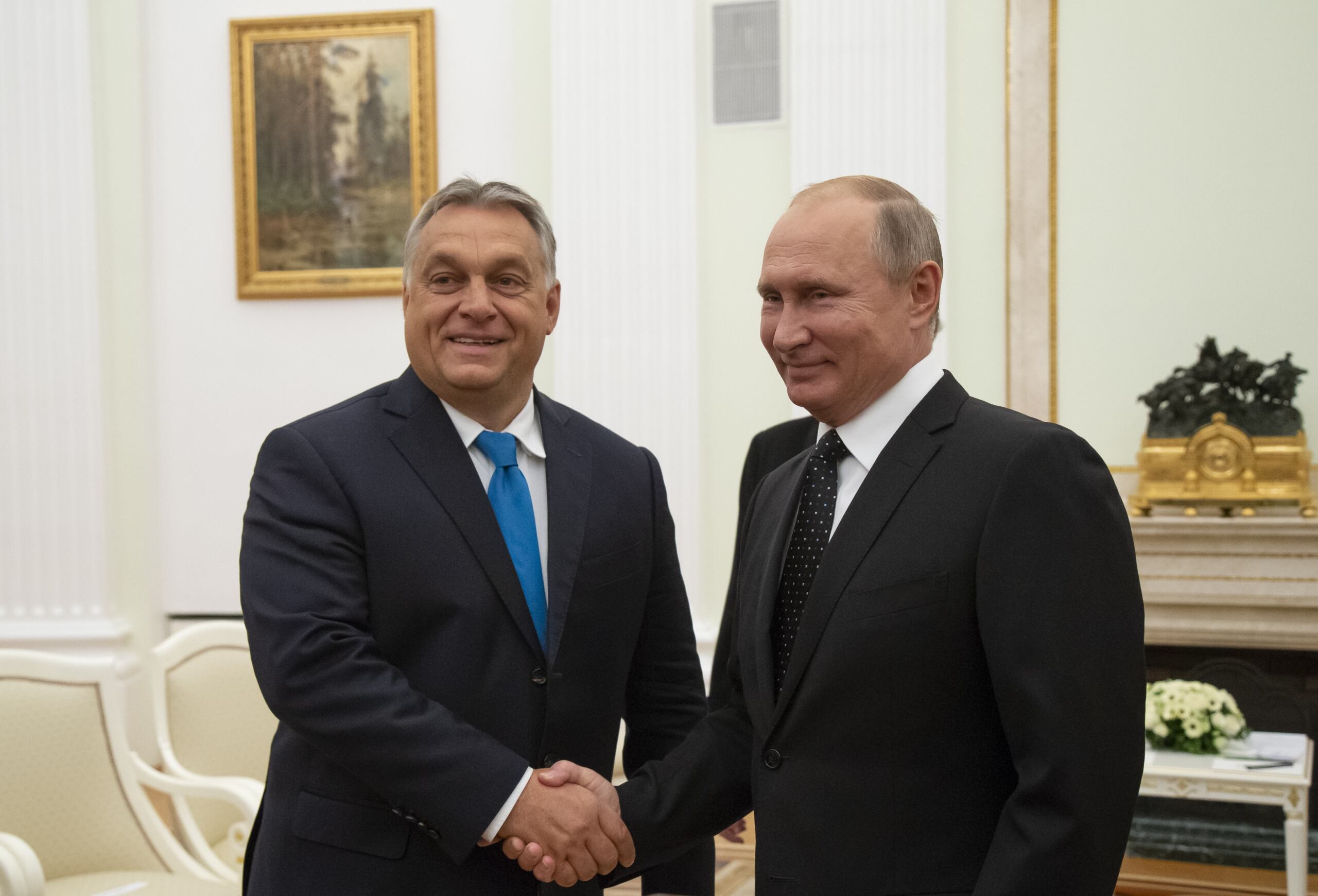 Dwaj mężczyźni ściskają sobie dłonie patrząc do kamery. To Viktor Orban i Władimir Putin