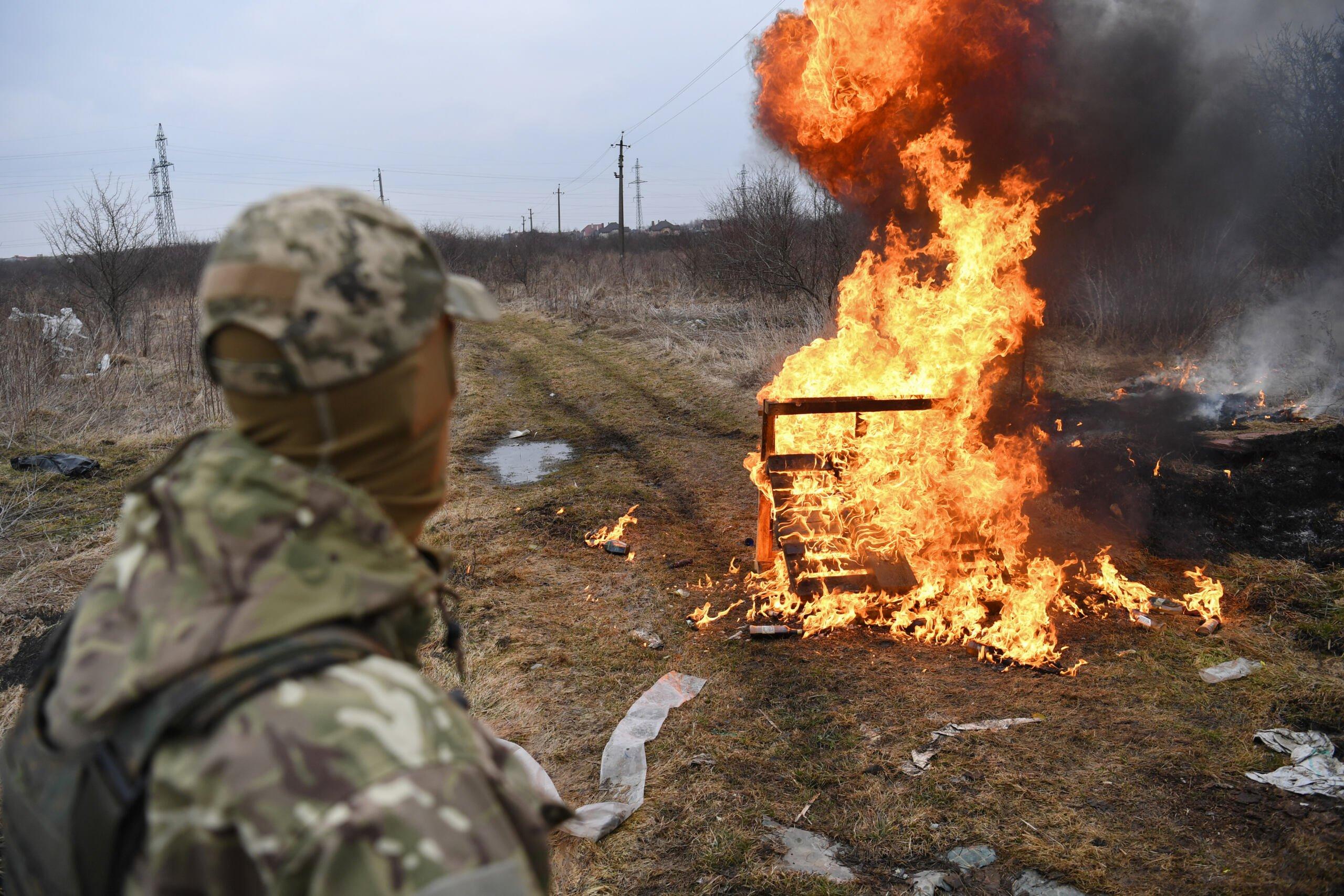 Ukraiński żołnierz patrzy na ogień po wybuchu koktajlu Mołotowa