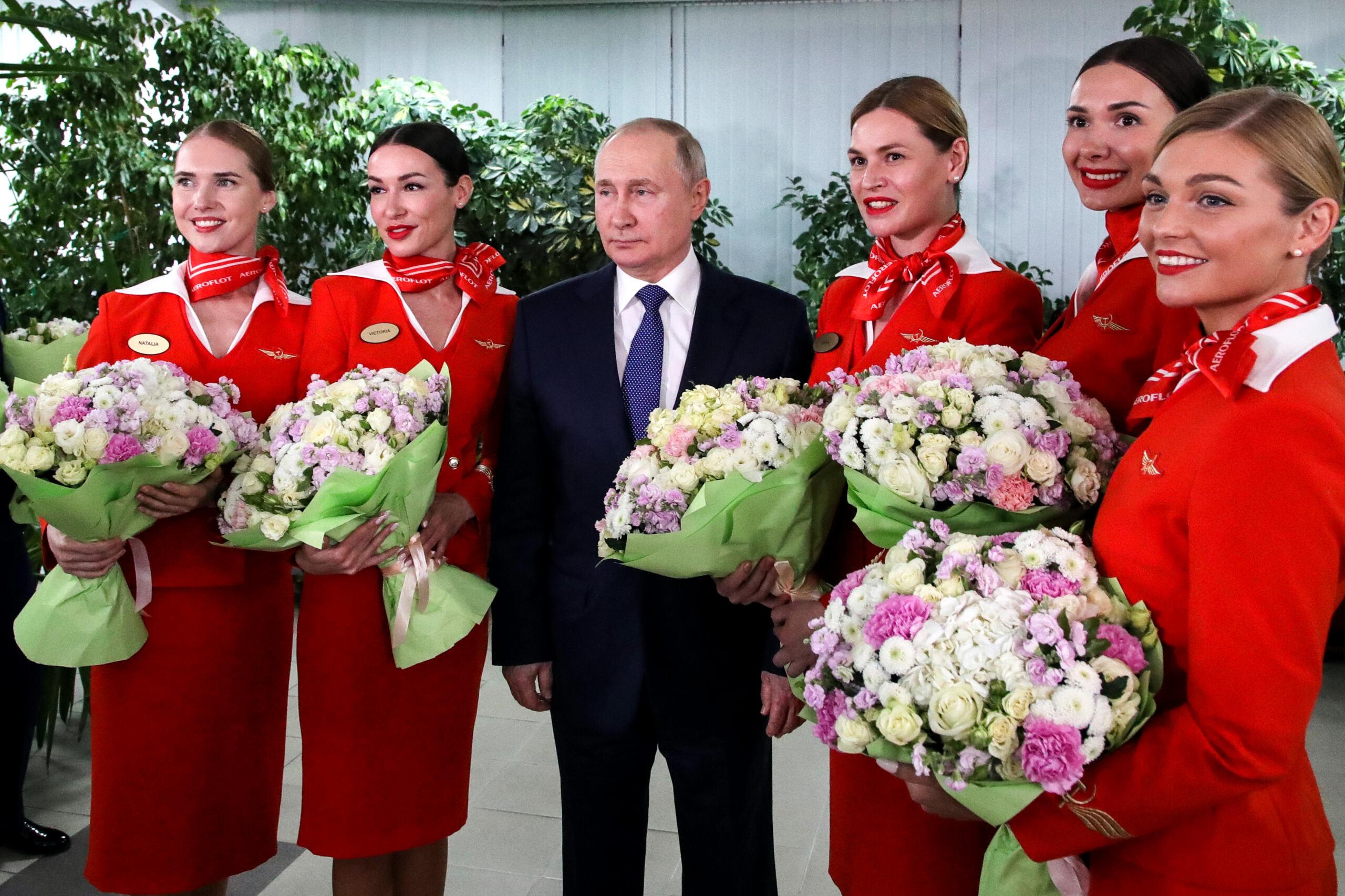Mężczyzna wśród stewardess z bukietami kwiatów